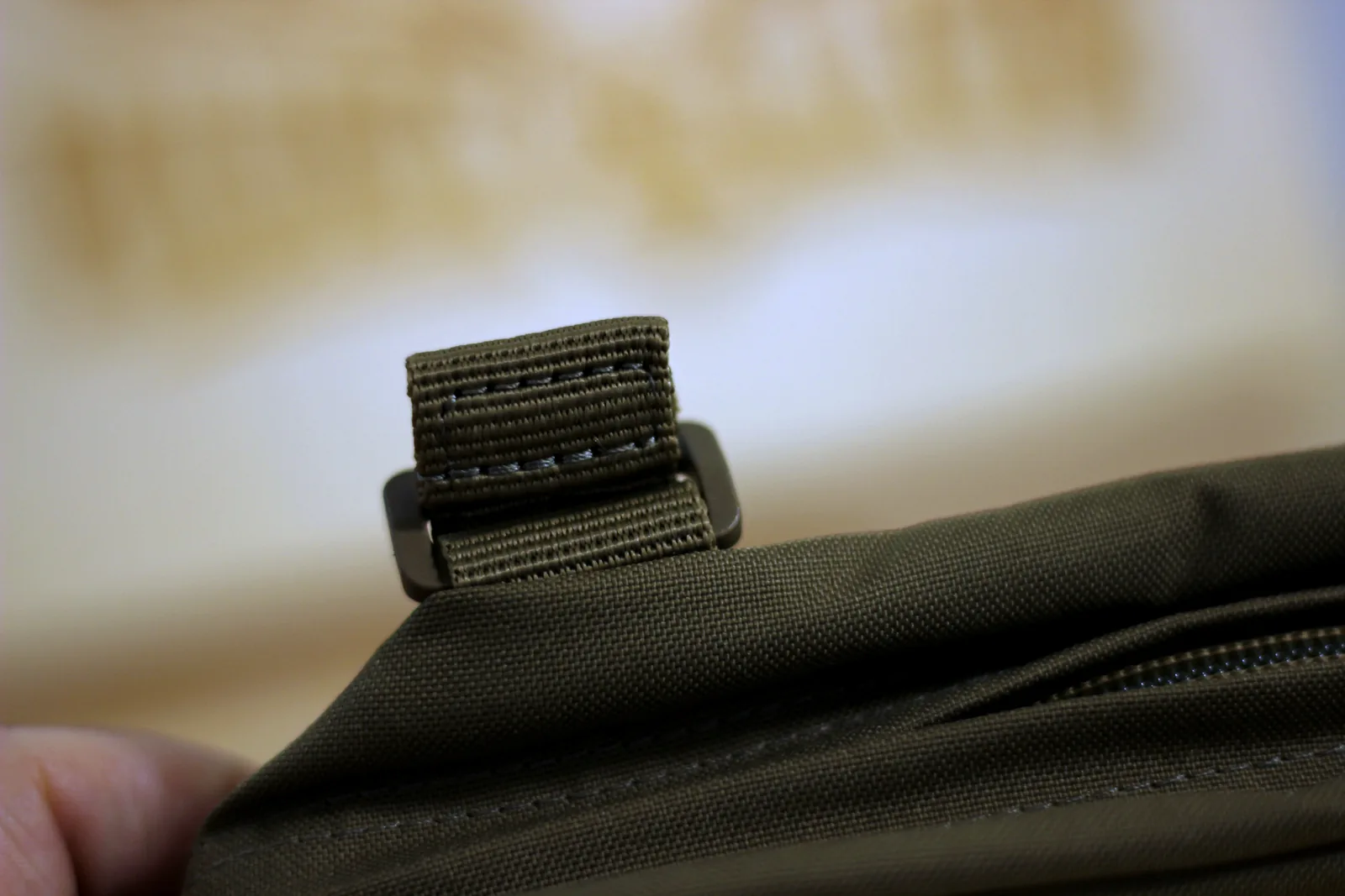 A single webbing mounting strap tab folded over on the back of the pouch