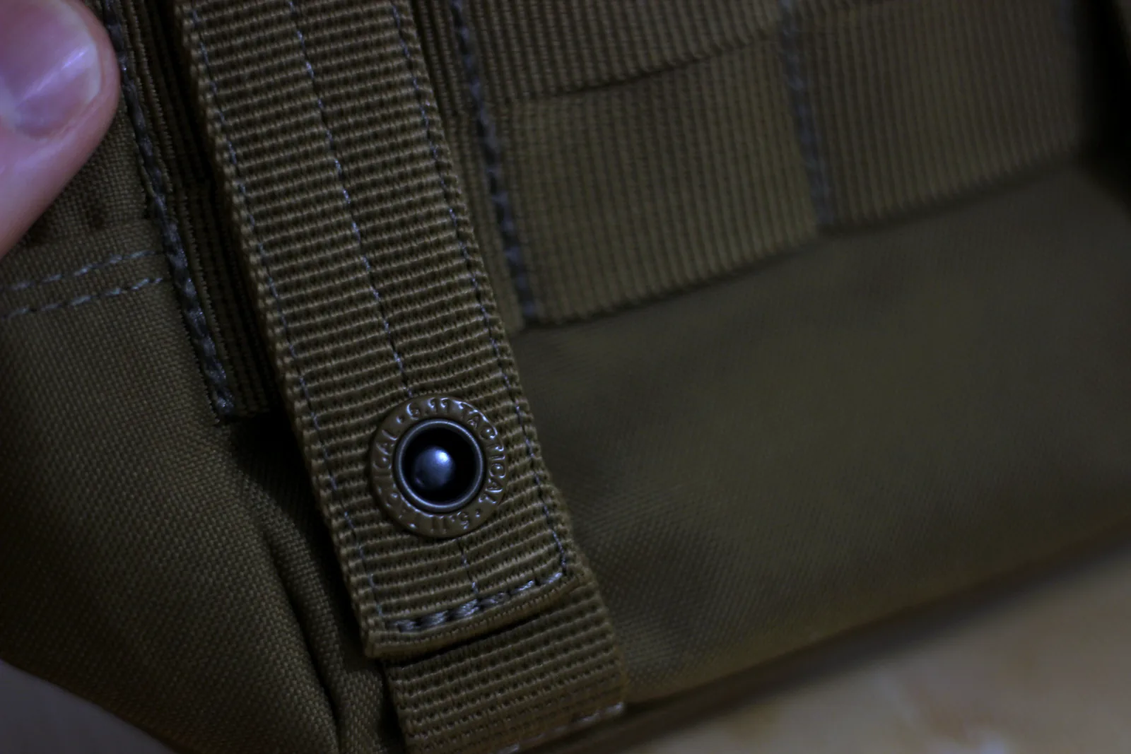 A metal snap closing the mounting strap on the back of the pouch