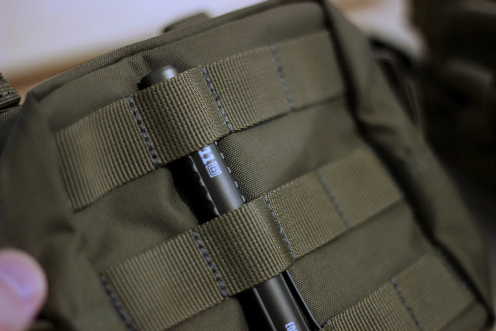 A 5.11 SlickStick rod threaded through the MOLLE webbing to mount the pouch