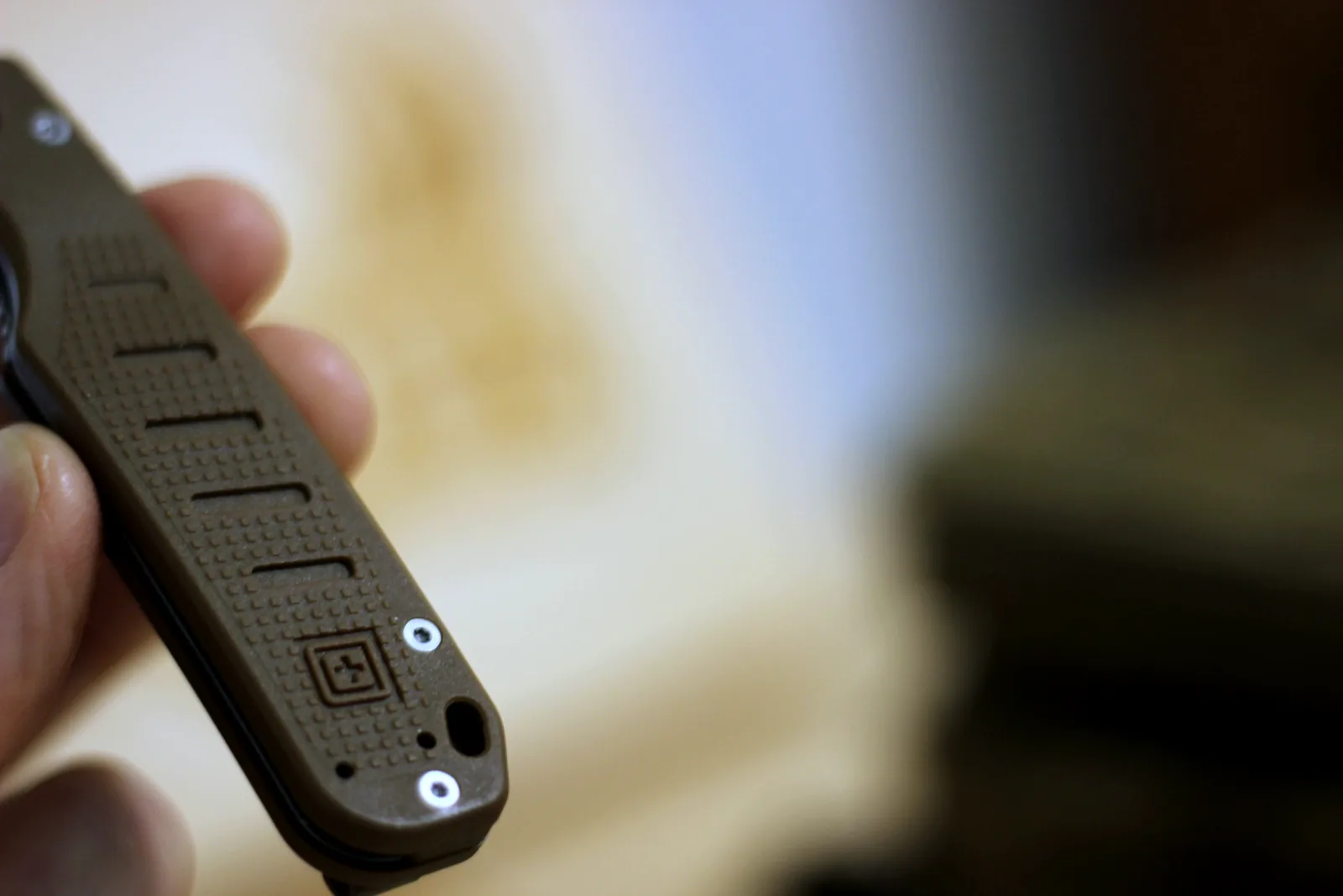 The textured FRN handle scales of the folding knife held in a hand