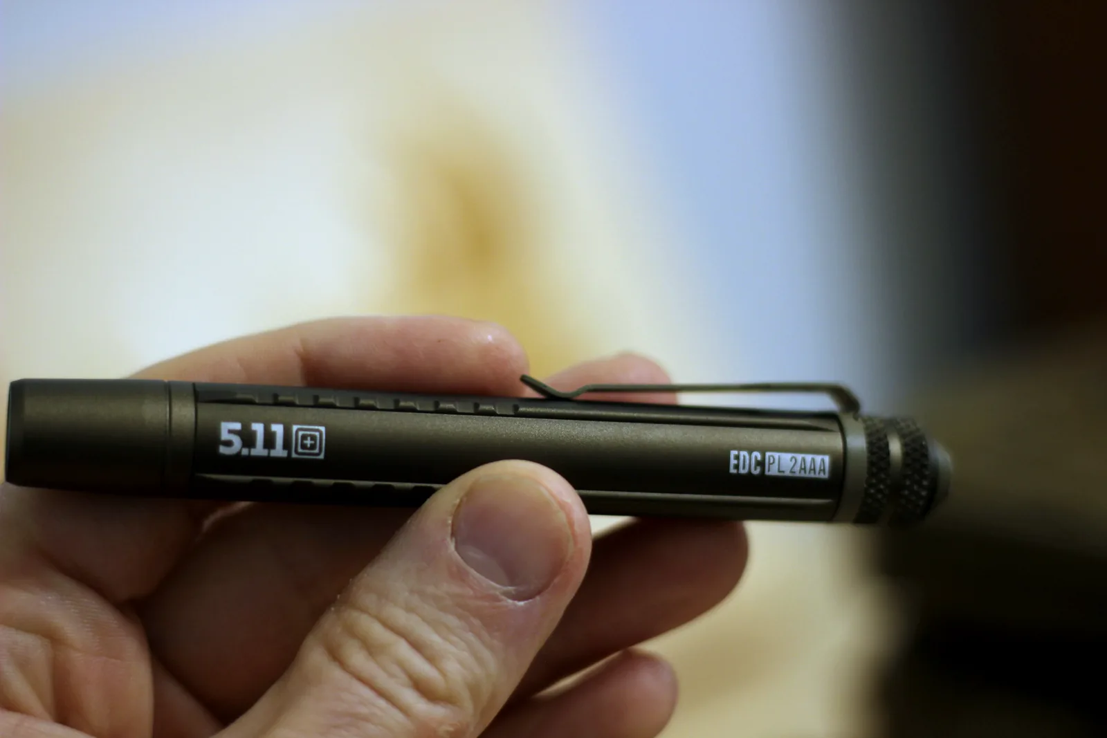 The slim anodised EDC PL 2AAA penlight held in a hand with the EDC PL 2AAA marking visible