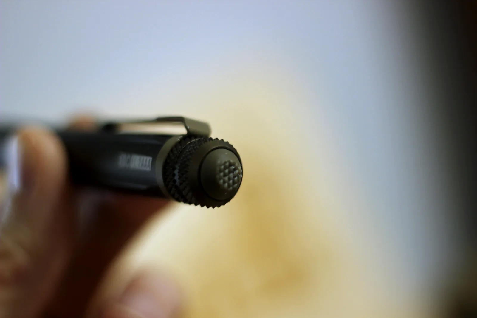 The knurled tail cap and pocket clip of the flashlight