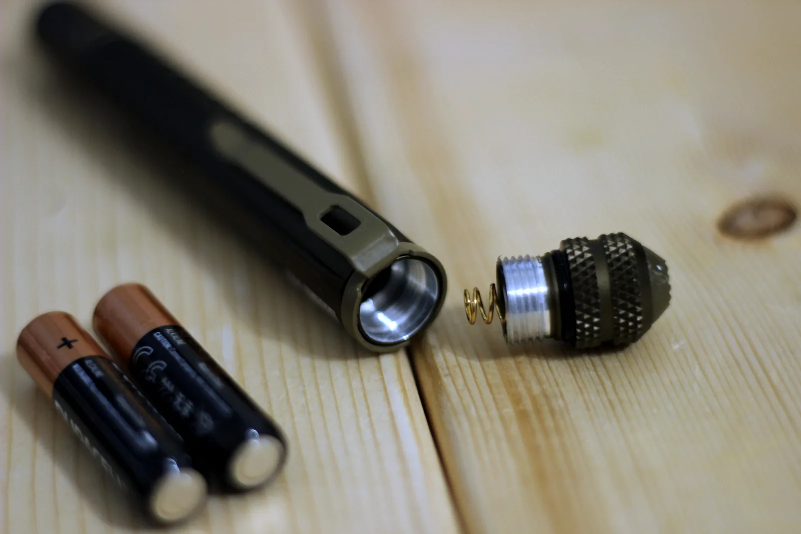 The flashlight unscrewed at the tail with two AAA batteries beside it