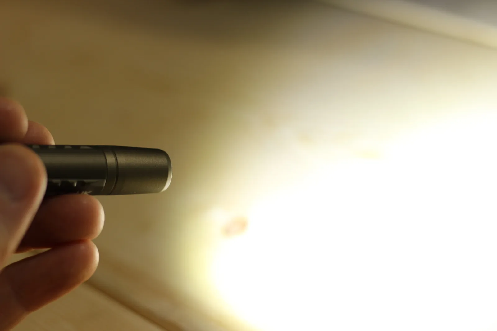 The flashlight switched on in the hand throwing a bright beam across a wooden bench