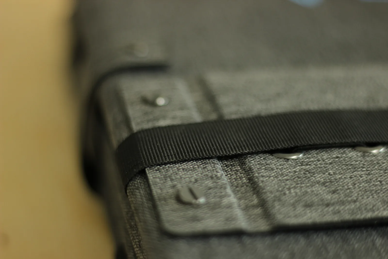 The folded edge of the panel showing black webbing running over the fabric with metal rivets set through it