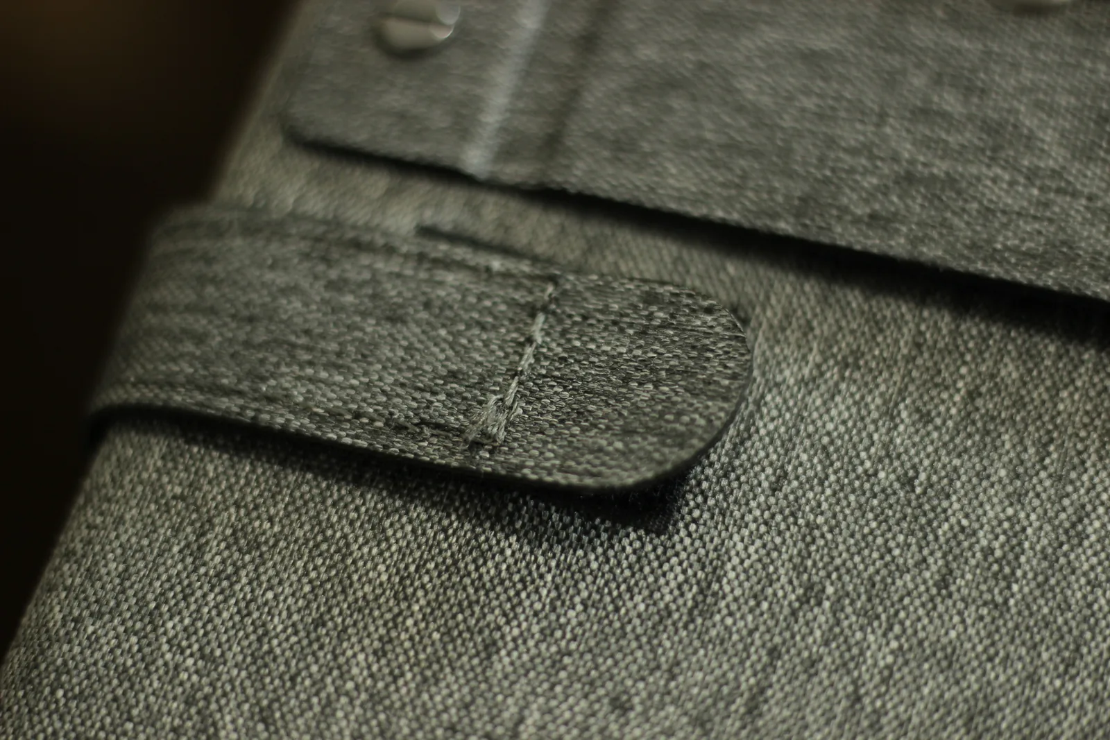 Macro of a fabric tab on the panel case showing the double row of stitching and bound edge