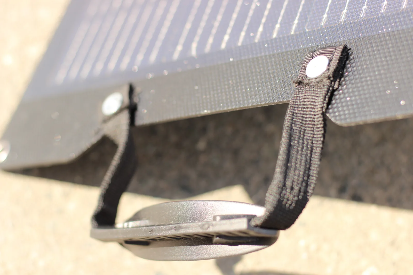 Close-up of the webbing strap and buckle that sets the kickstand angle, seen against the sunlit panel edge