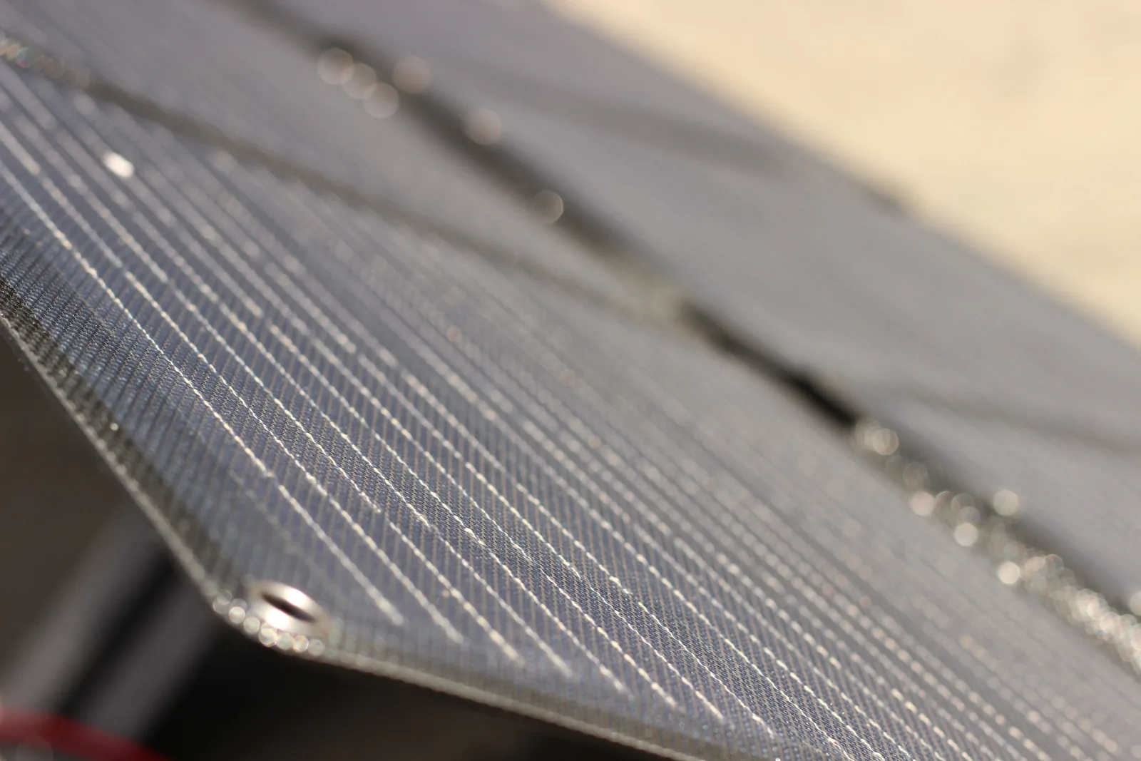 The panel surface photographed in raking sunlight, the textured lamination catching the light across the cell array