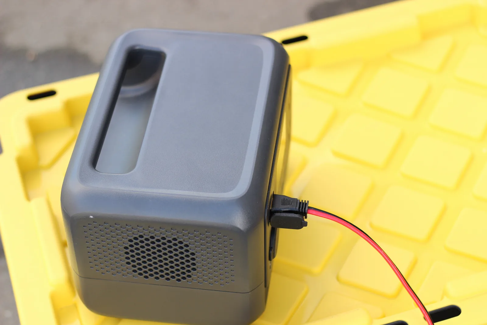 The BLUETTI Elite 30 from above on a yellow tote lid with the red and black solar lead plugged into its side