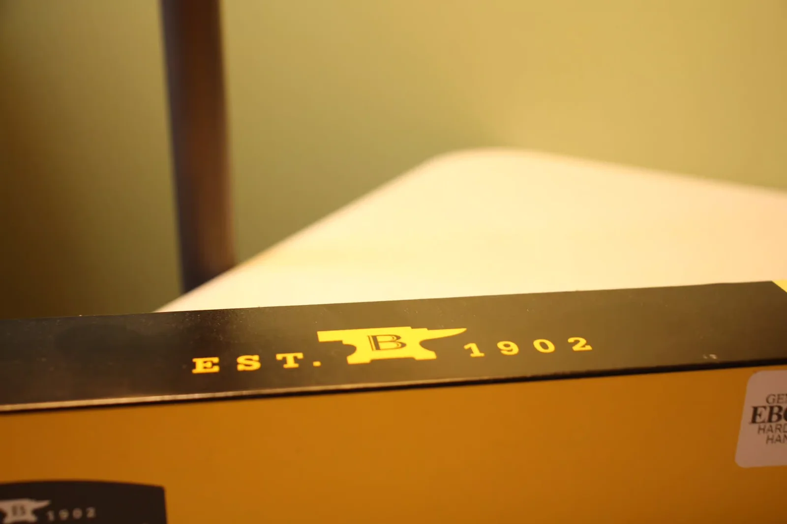 Close-up of the gold 'EST. 1902 B anvil' branding on the top of the Buck box