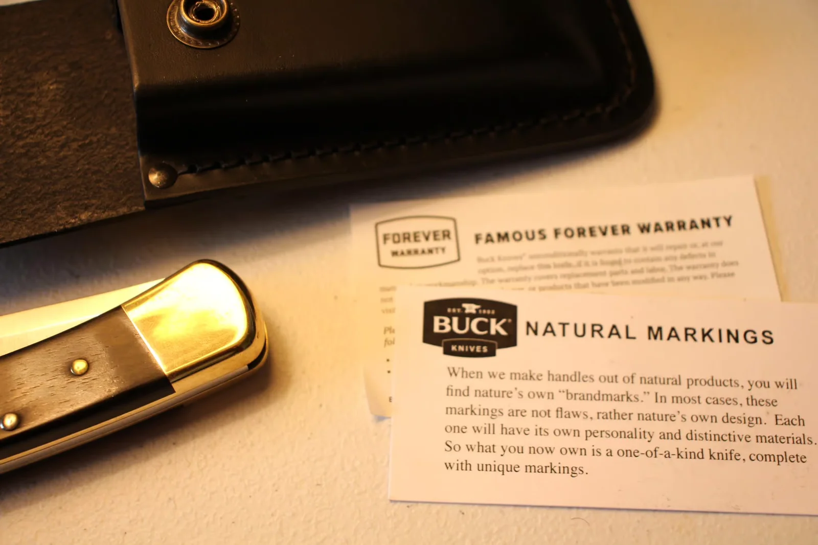 Open box showing leather sheath, Forever Warranty card, and Natural Markings card on Buck letterhead