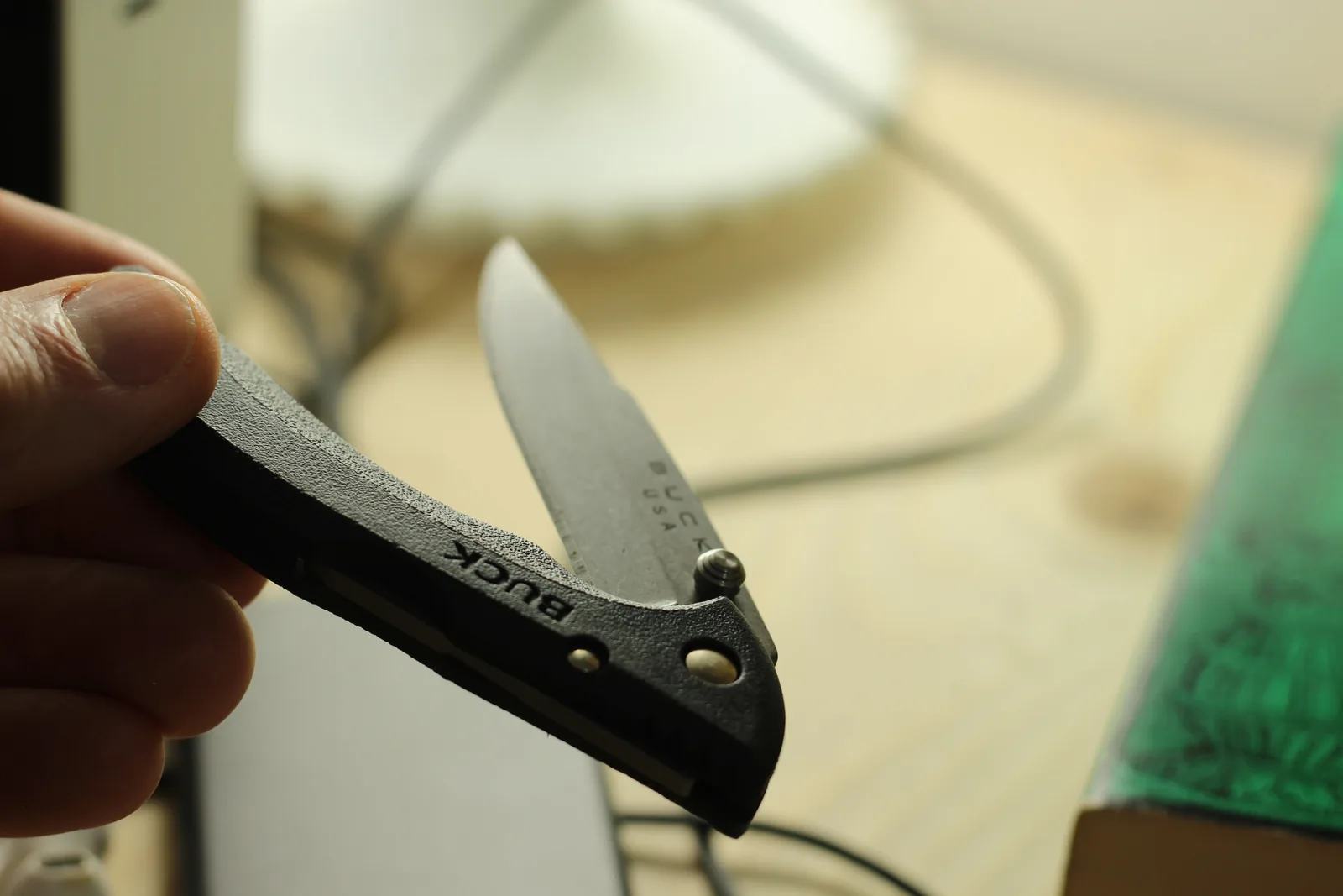The knife held with the blade about a third open and a thumb on the stud