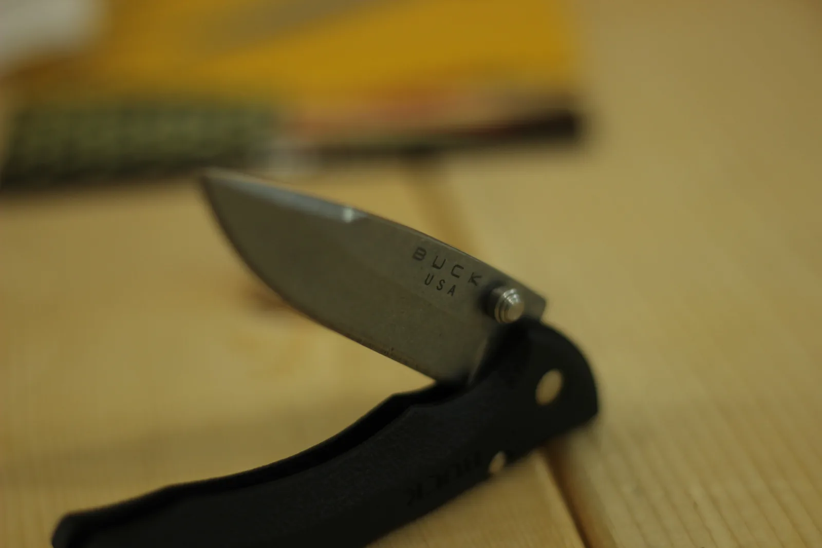 Low-angle view of the open knife on the bench with the yellow packaging out of focus behind