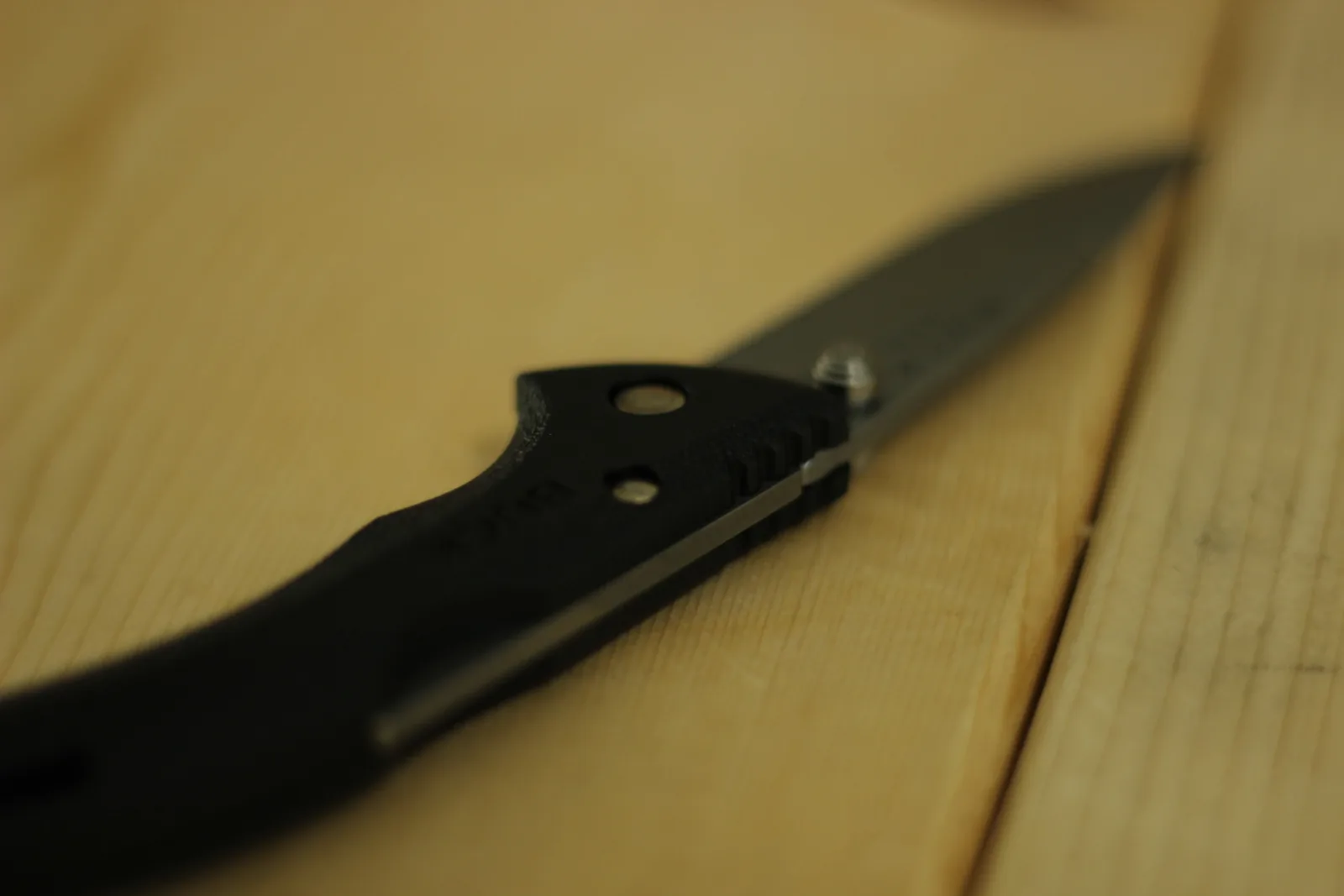 Angled view down the closed knife showing the lanyard hole through the handle and the ridged spine section
