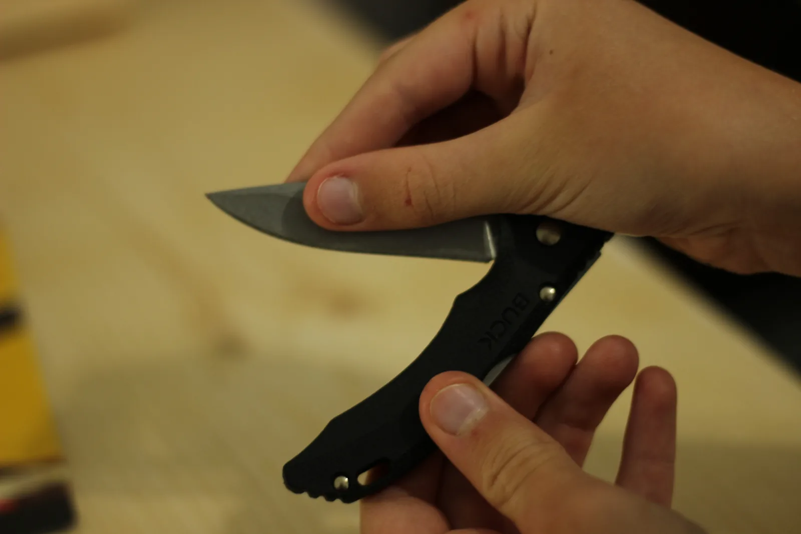 Two hands closing the knife, one pressing the lock bar on the spine while the other guides the blade