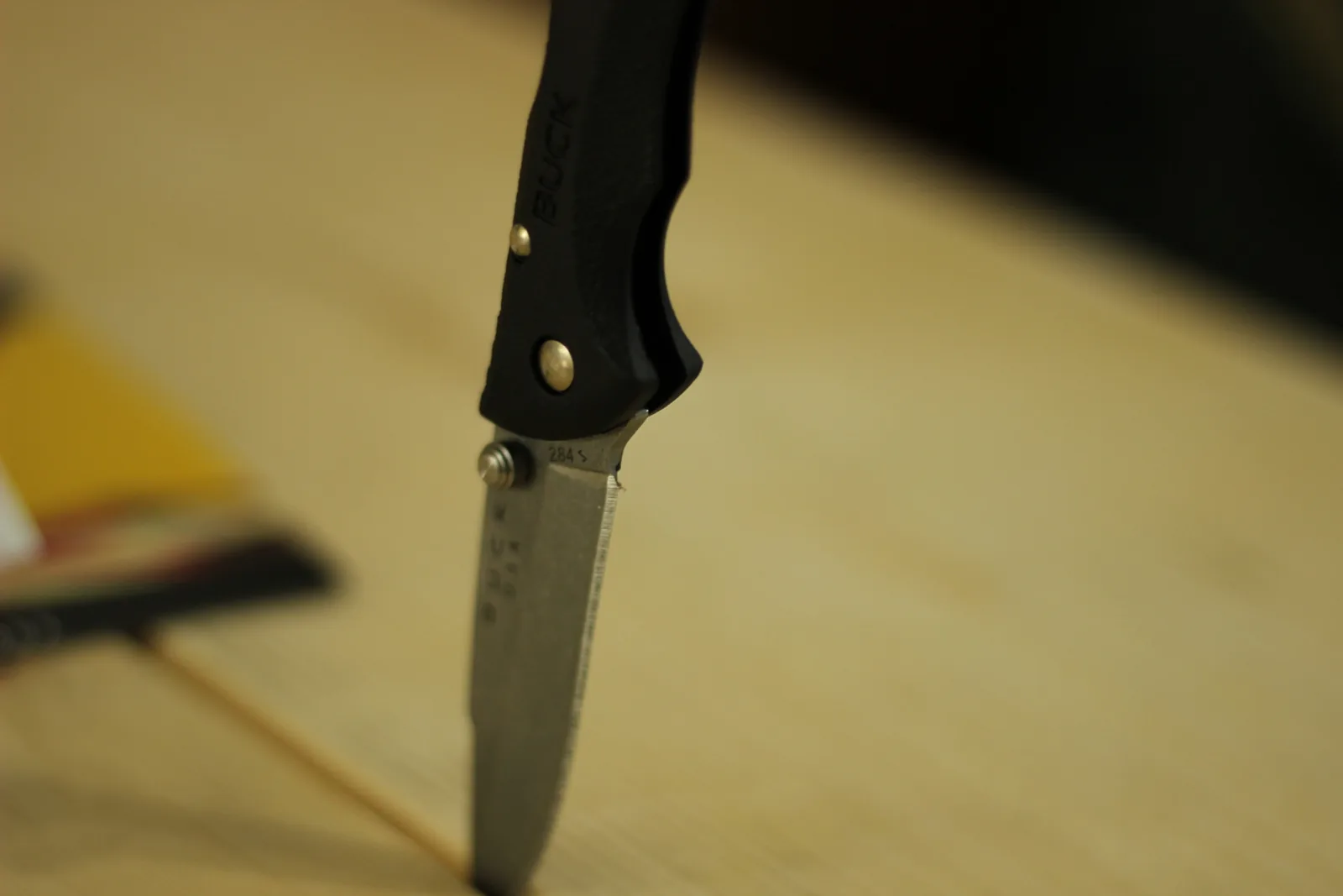 The open knife balanced on its tip on a wooden bench with the 284 stamp and a letter code readable near the pivot