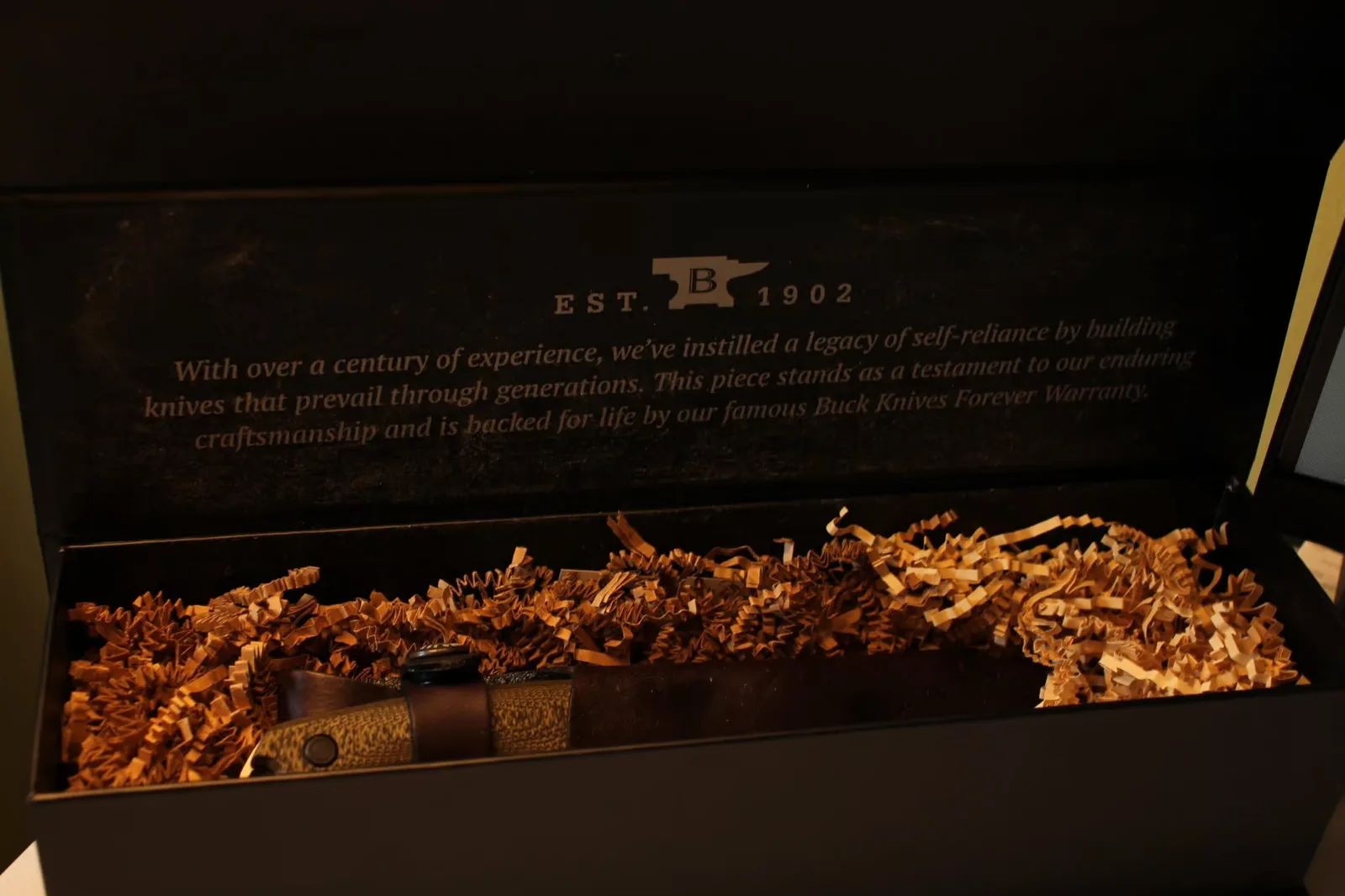 Open Buck box showing crinkle paper and Est. 1902 branding inside