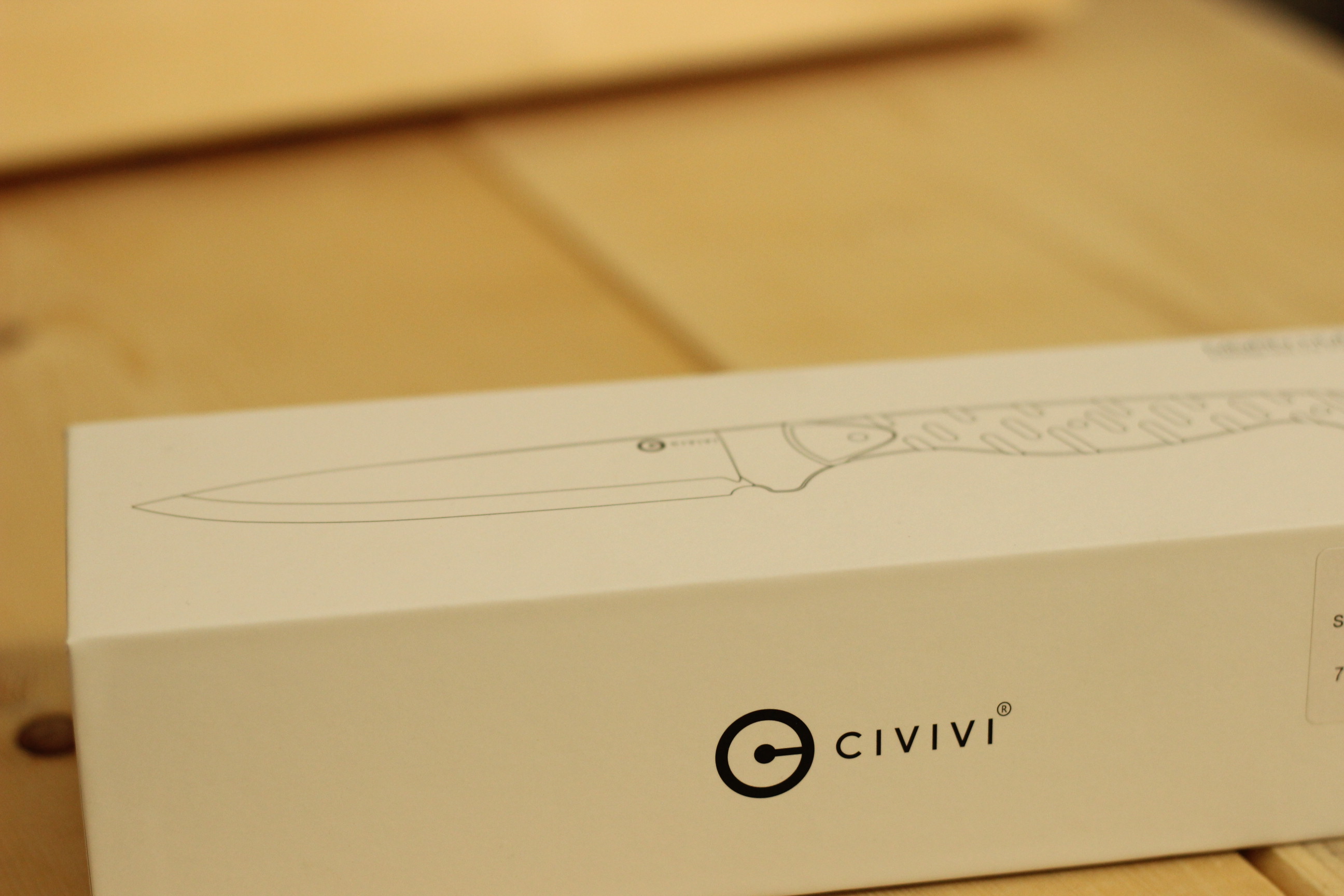 The Civivi MDRN Hunter retail box sitting on a light-wood plank surface with the Civivi wordmark and a line-art rendering of the knife etched in single colour across the side of the box