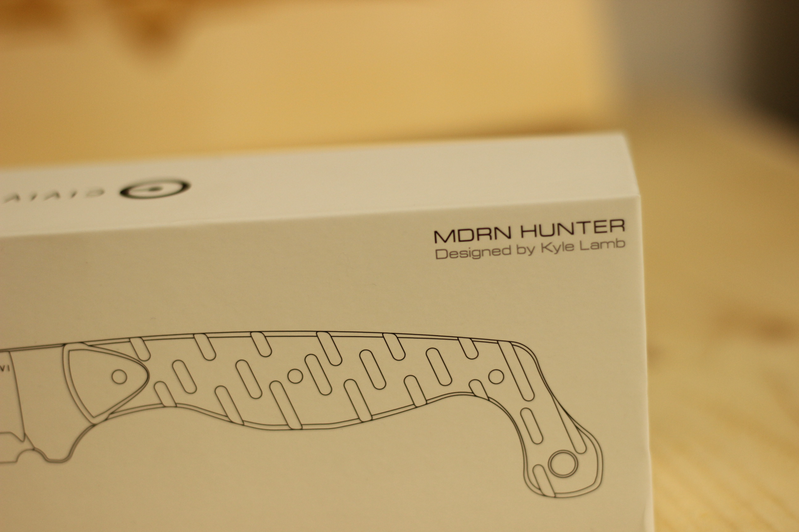 Close-up of the Civivi MDRN Hunter box showing the MDRN HUNTER wordmark and Designed by Kyle Lamb credit printed in small text beside a line-art rendering of the handle
