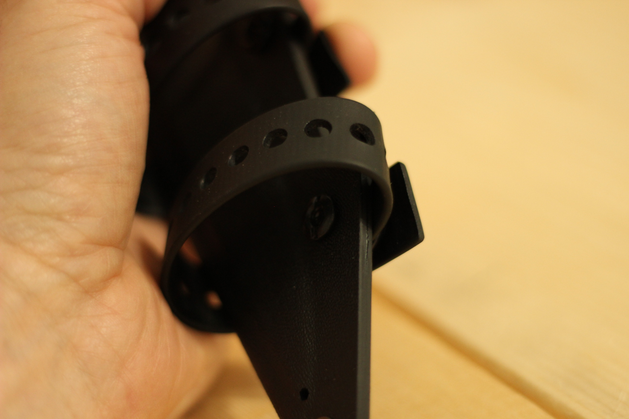 Close-up of the polymer carrier strap on the Civivi MDRN Hunter kydex sheath showing the perforated polymer strap with its hole pattern, the rivet at the base of the strap, and the inner kydex panel of the sheath