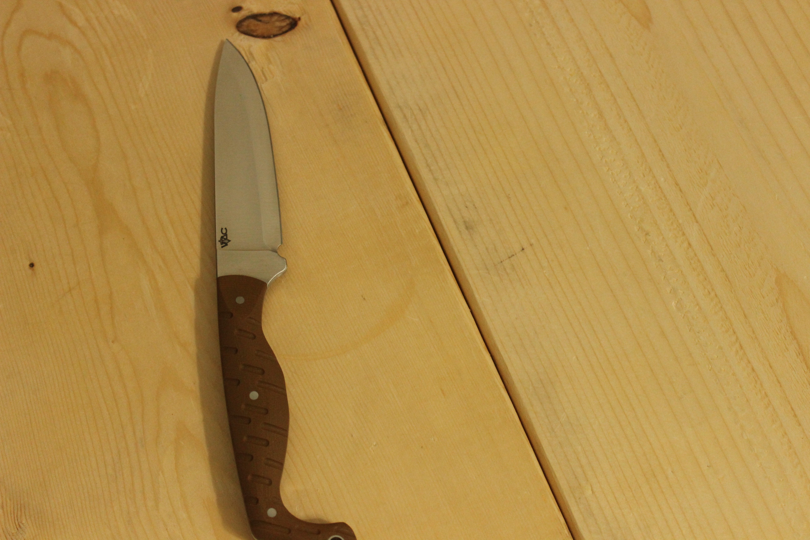 The Civivi MDRN Hunter laid flat on a light pine workbench, blade pointing up, the satin steel and the warm brown G10 handle catching even side light across the full length of the knife