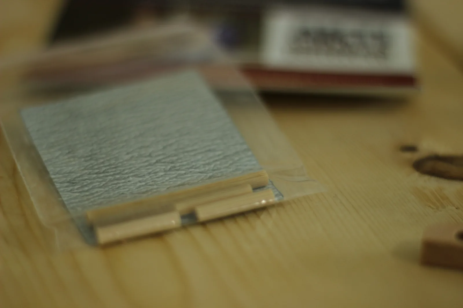 A small sealed plastic bag containing a square of grey sandpaper and several lengths of wooden dowel