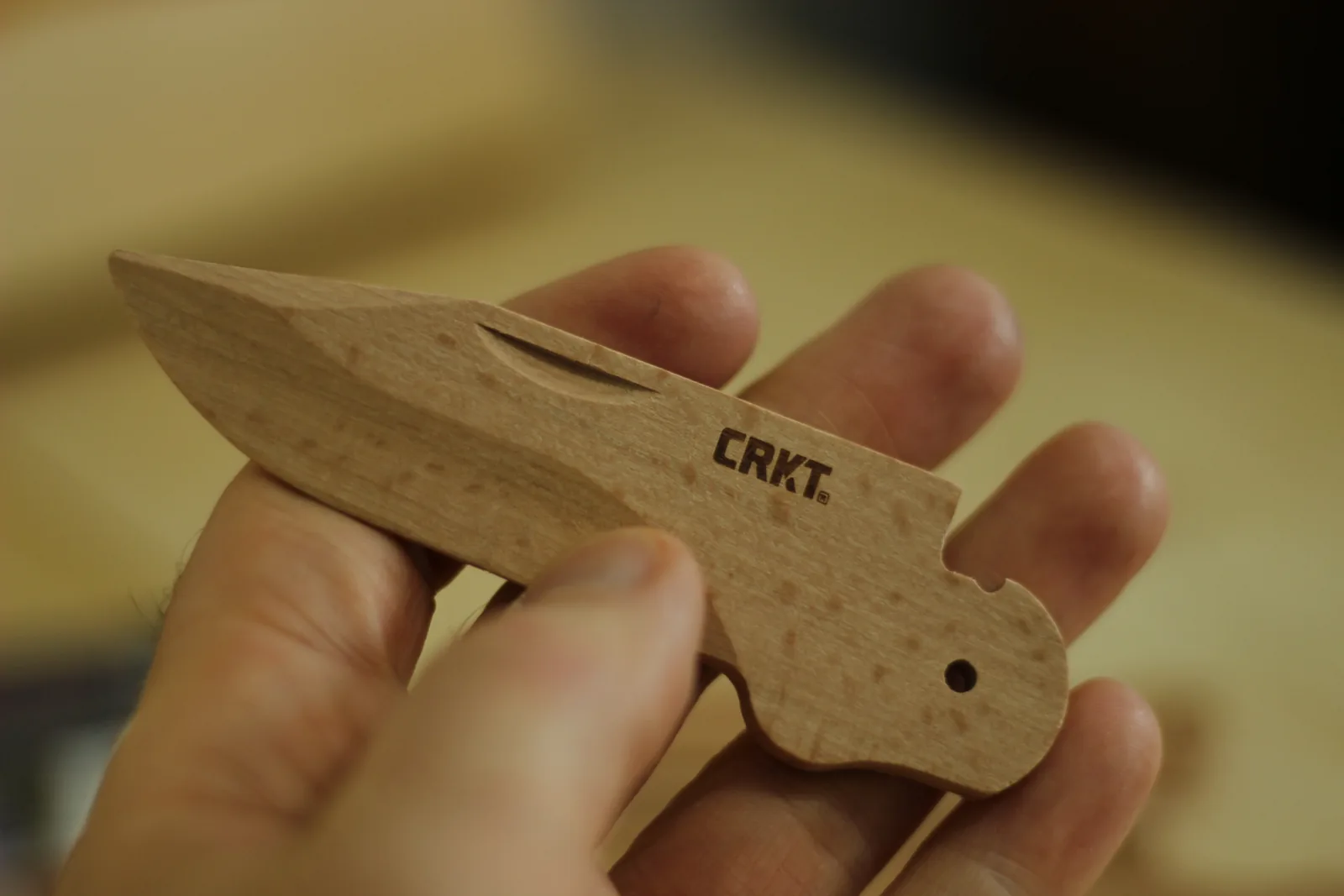 The beech blade held in a hand, showing the drop-point profile, the ground bevel and the notch cut into the spine for the lock
