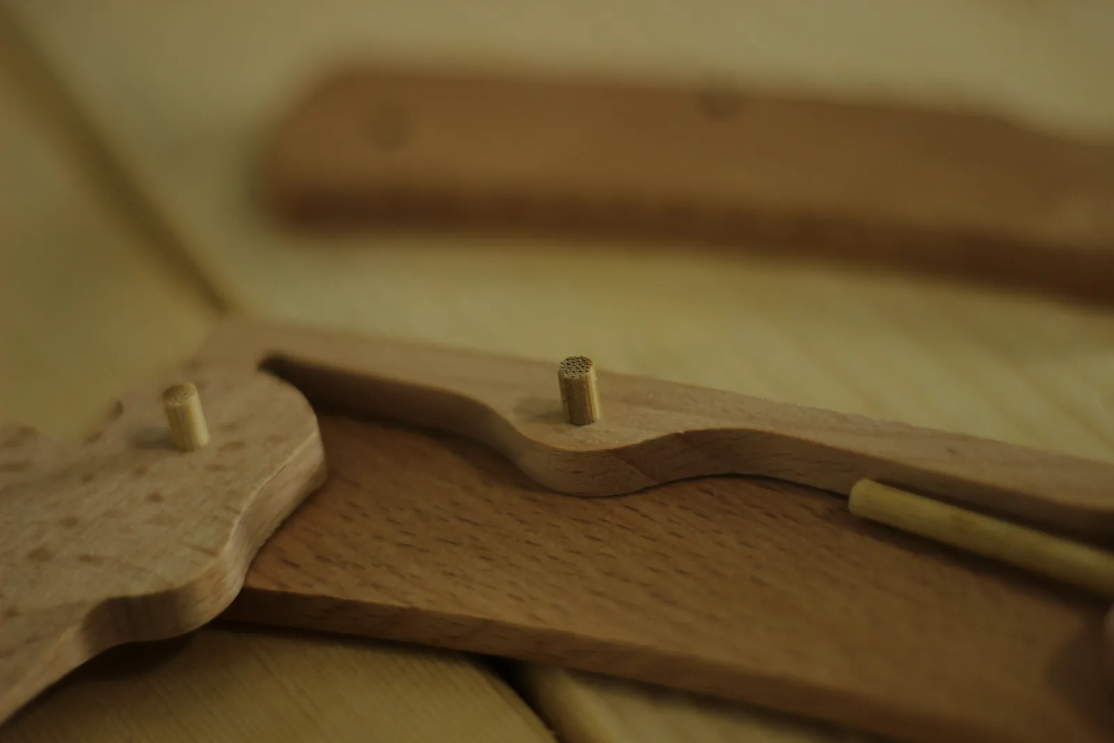 Two dowel pins standing upright out of a beech handle scale with the lock bar seated between them
