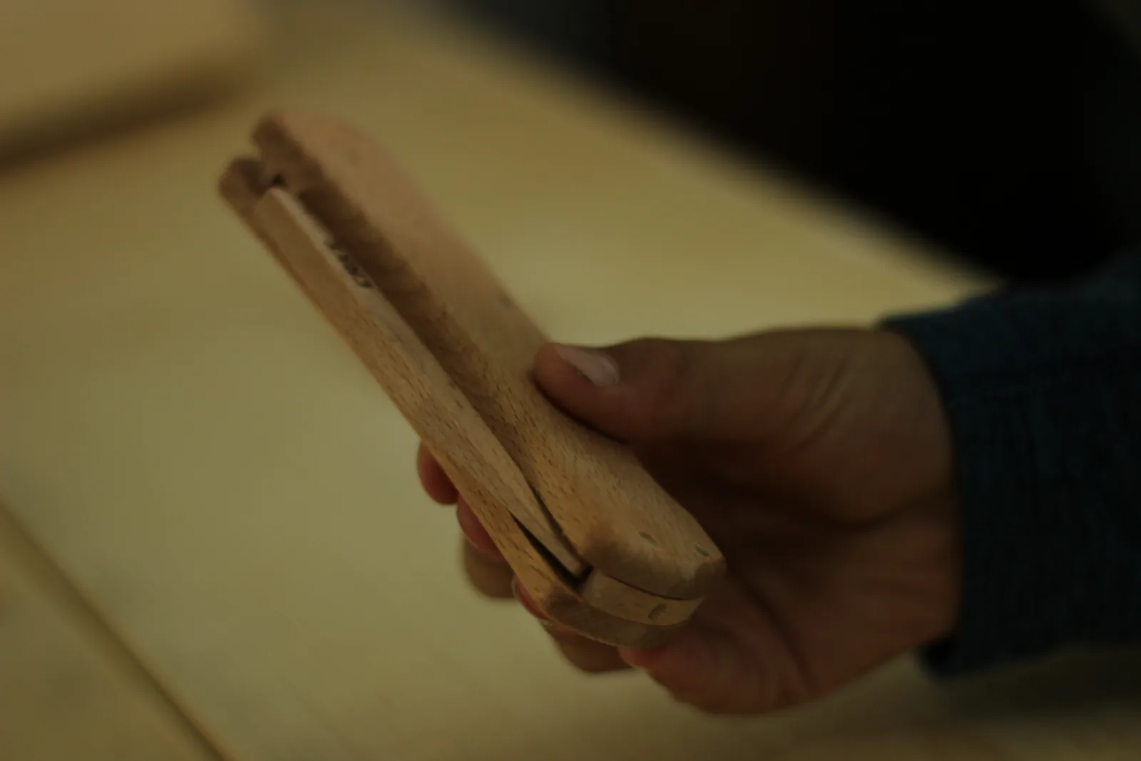 The finished wooden folding knife held closed in a hand, showing the seam where the blade sits down inside the handle