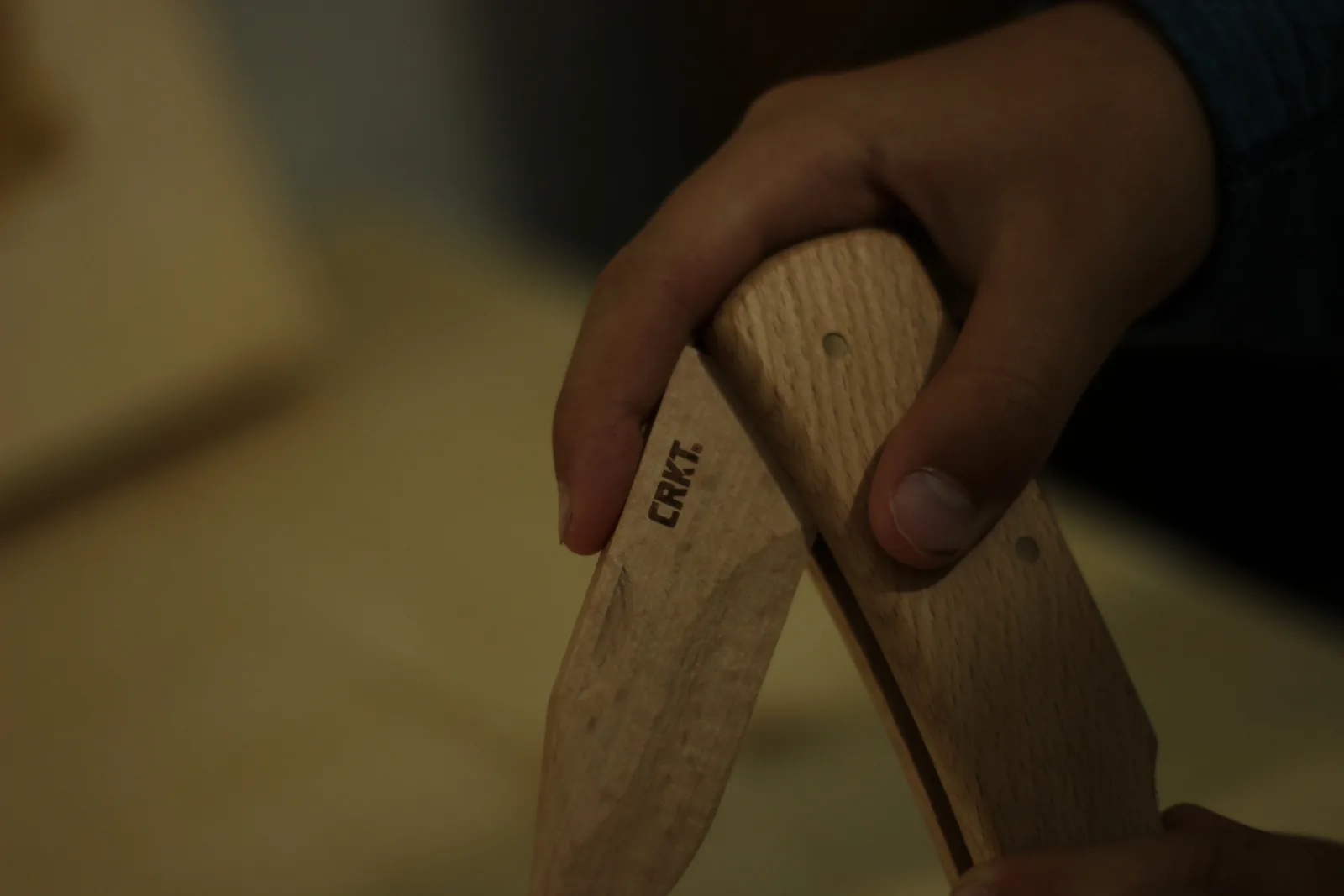The wooden knife held with the blade open at roughly ninety degrees to the handle
