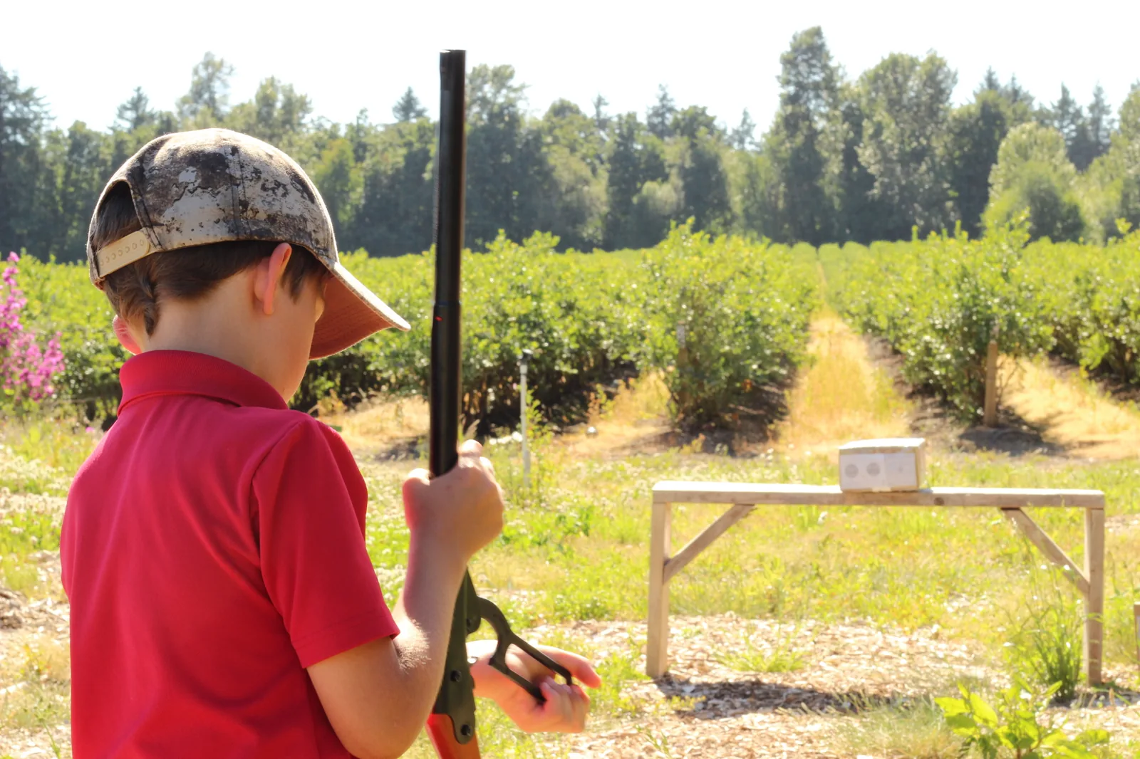 Wider view of the shooter aiming at the target with the field in context