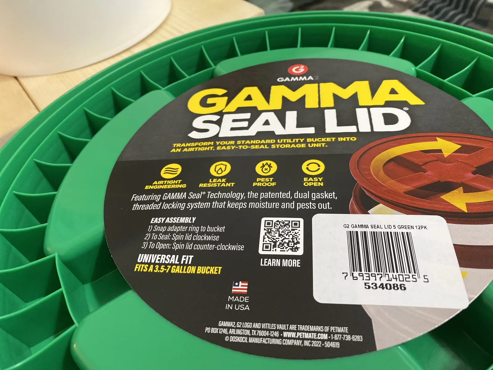Close-up of the GAMMA Seal Lid retail label showing transform-your-standard-utility-bucket text, UPC code, QR code, and Universal Fit 3.5-7 gallon designation