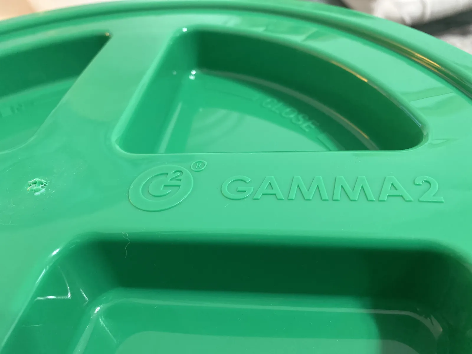 Close-up of the molded "G²" logo and "GAMMA2" wordmark embossed into the top deck of the green GAMMA Seal Lid