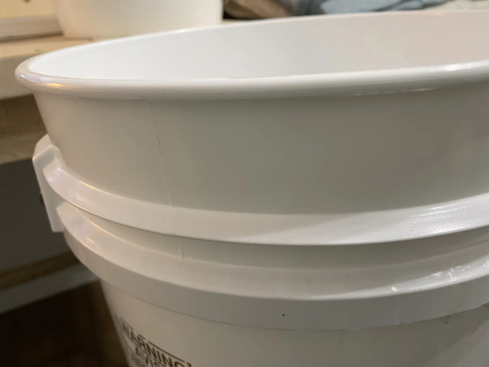 Hand grasping the GAMMA Seal Lid by the molded handle recess at the top, ready to spin it on or off