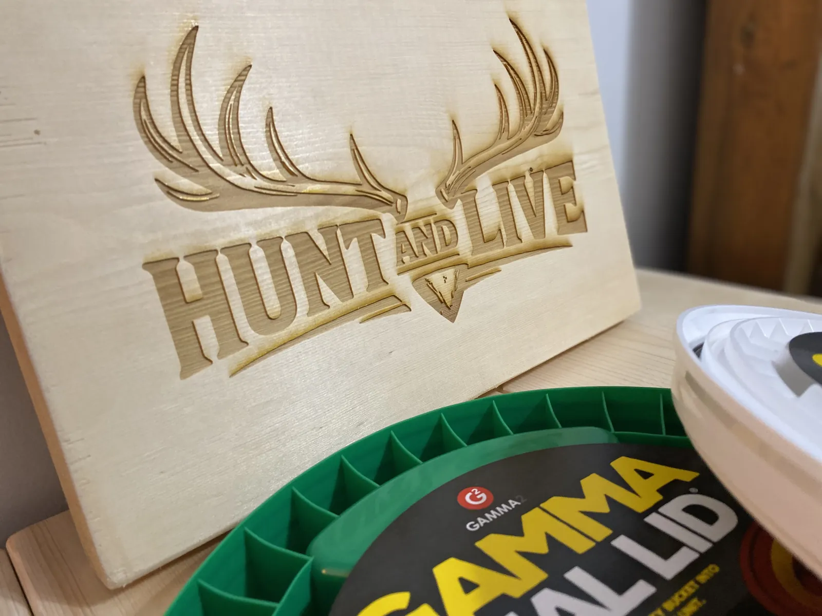 Edge-on view of the GAMMA Seal Lid threads with the Hunt & Live wood plaque visible in the background