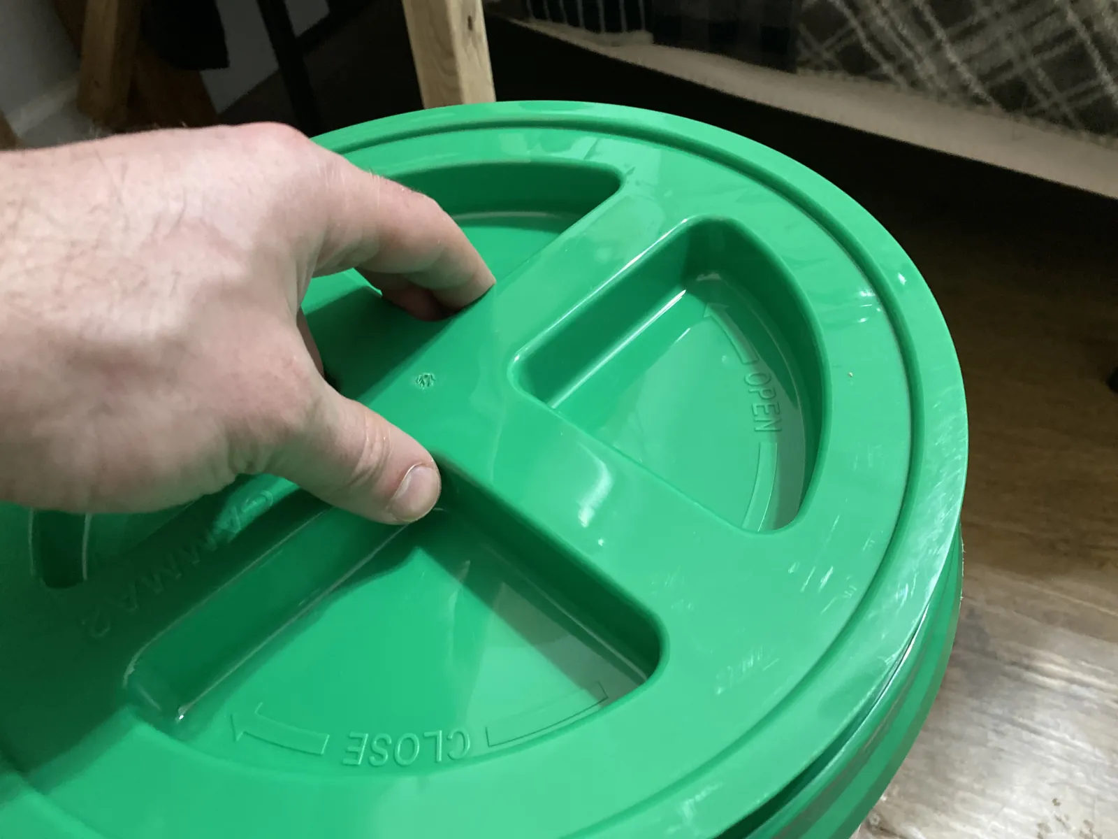 Top view of the GAMMA Seal Lid in green sitting on top of a 5-gallon white bucket showing the four spoke-divider handles on the top deck