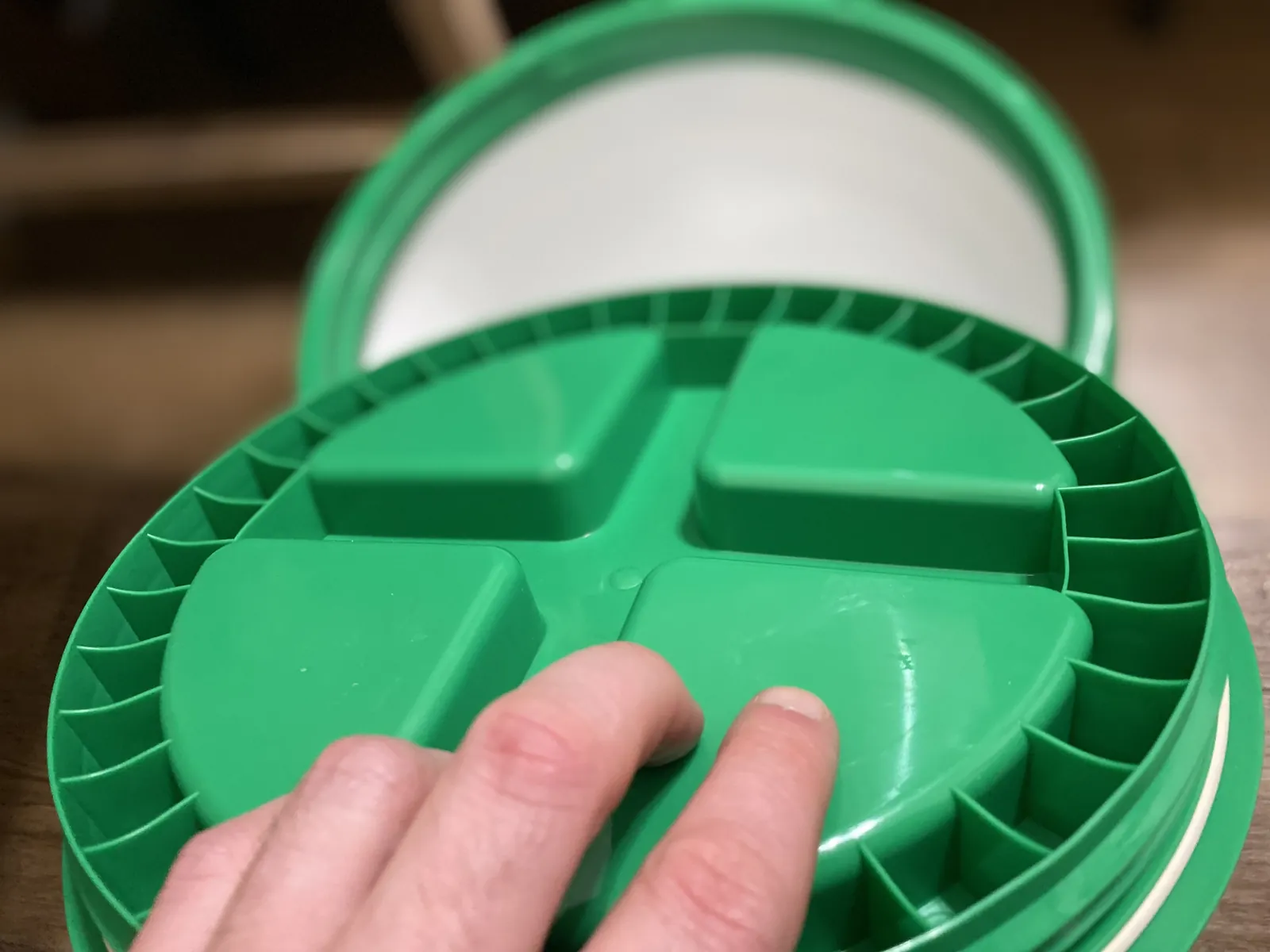 Close-up underside of the GAMMA Seal Lid showing the molded spoke pattern with a finger on the inner deck for scale