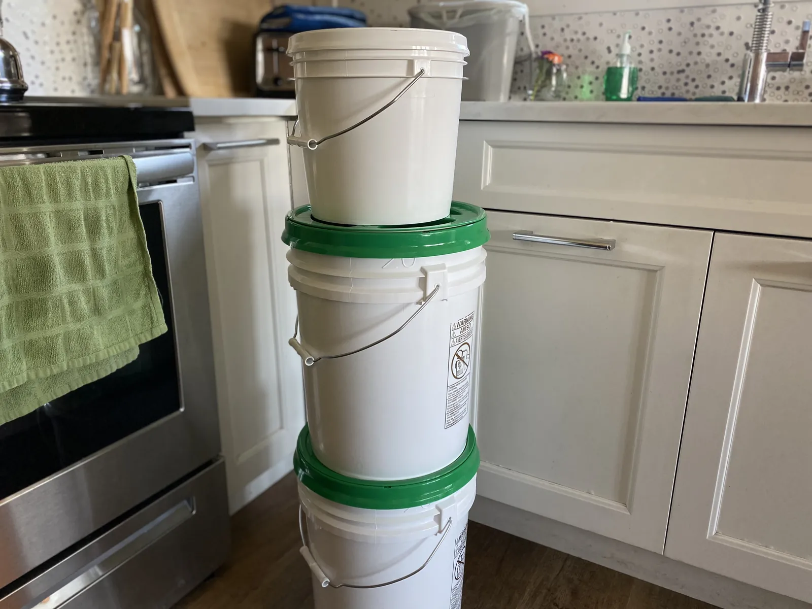 Bottom of a 2-gallon white bucket showing the embossed manufacturer stamps: KIRK CONTAINERS, Commerce CA 90040, HDPE recycling code, NRC .065 MIL, 2 U.S. GALLONS