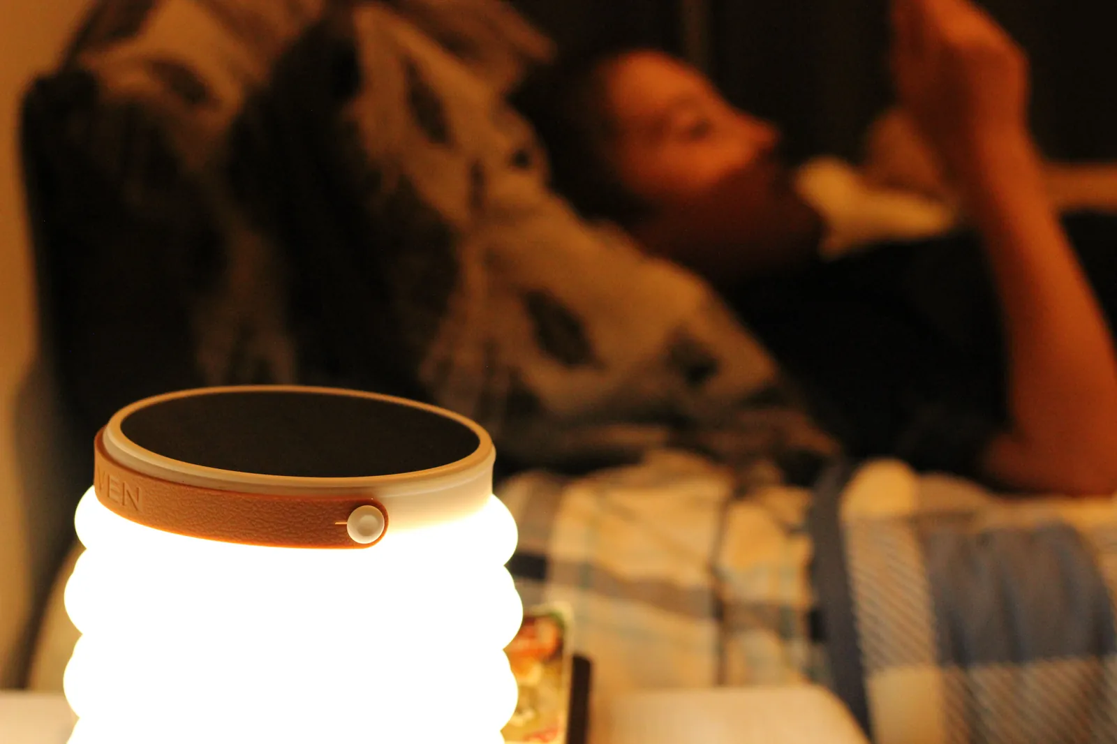 HAVEN 10000 on a bedside table providing reading light, person reading in the background