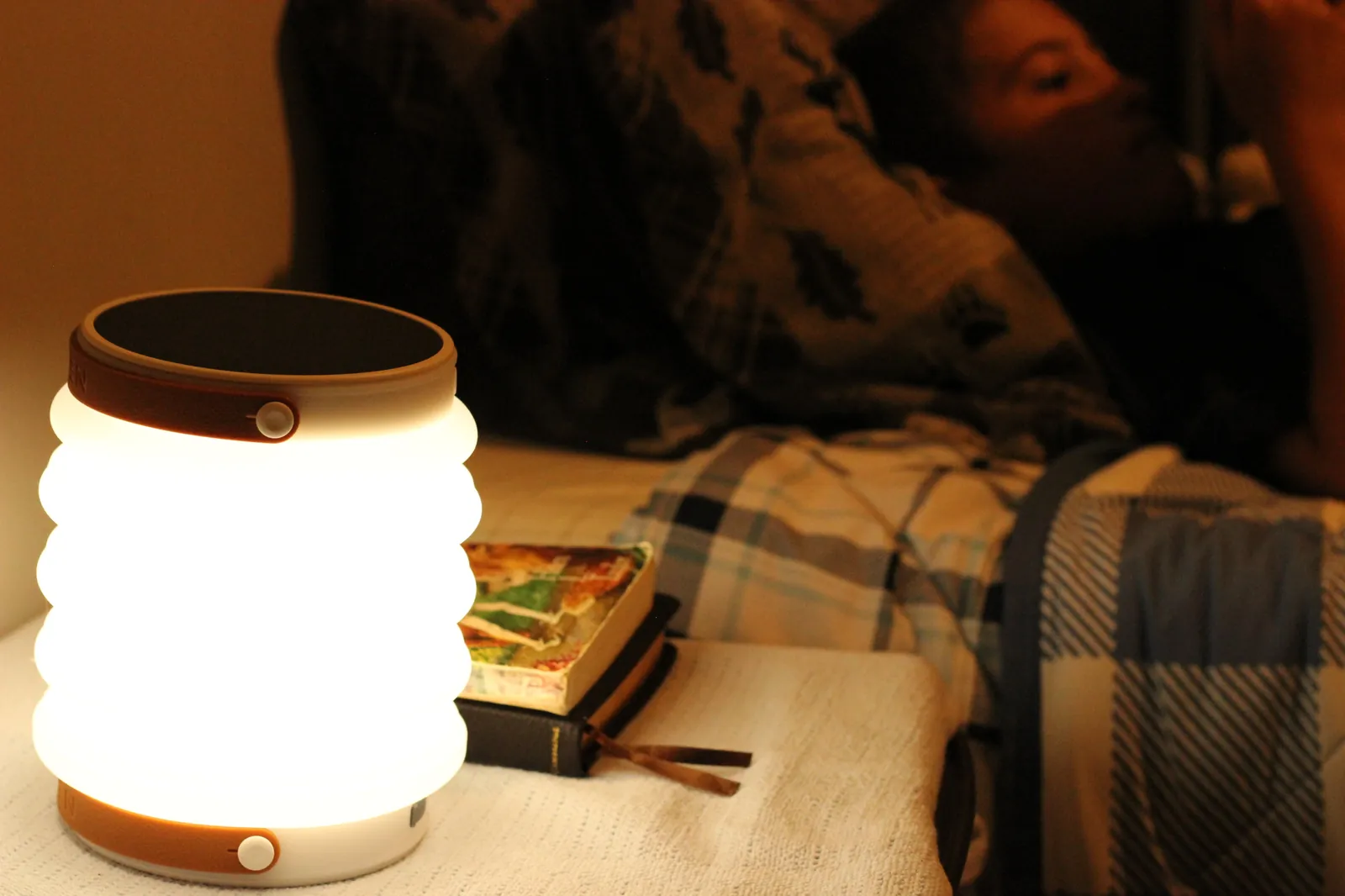 HAVEN 10000 lit at bedside with book and person resting on couch in background