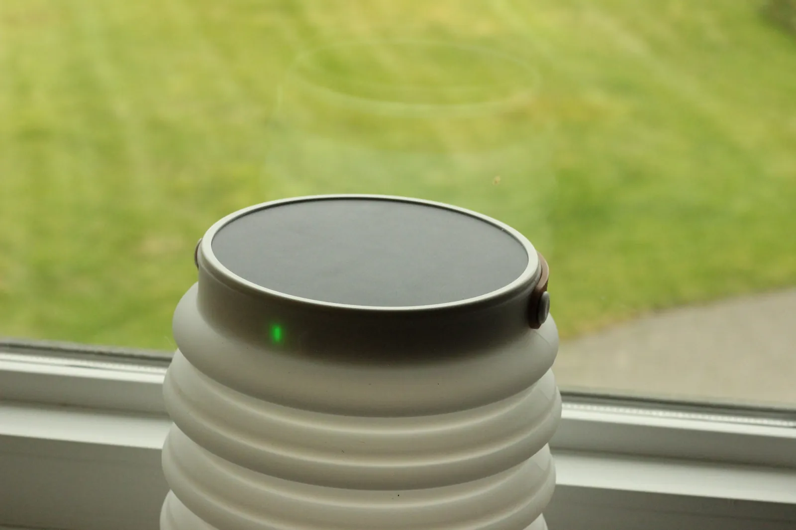 HAVEN 10000 charging on a windowsill with view of green grass outside