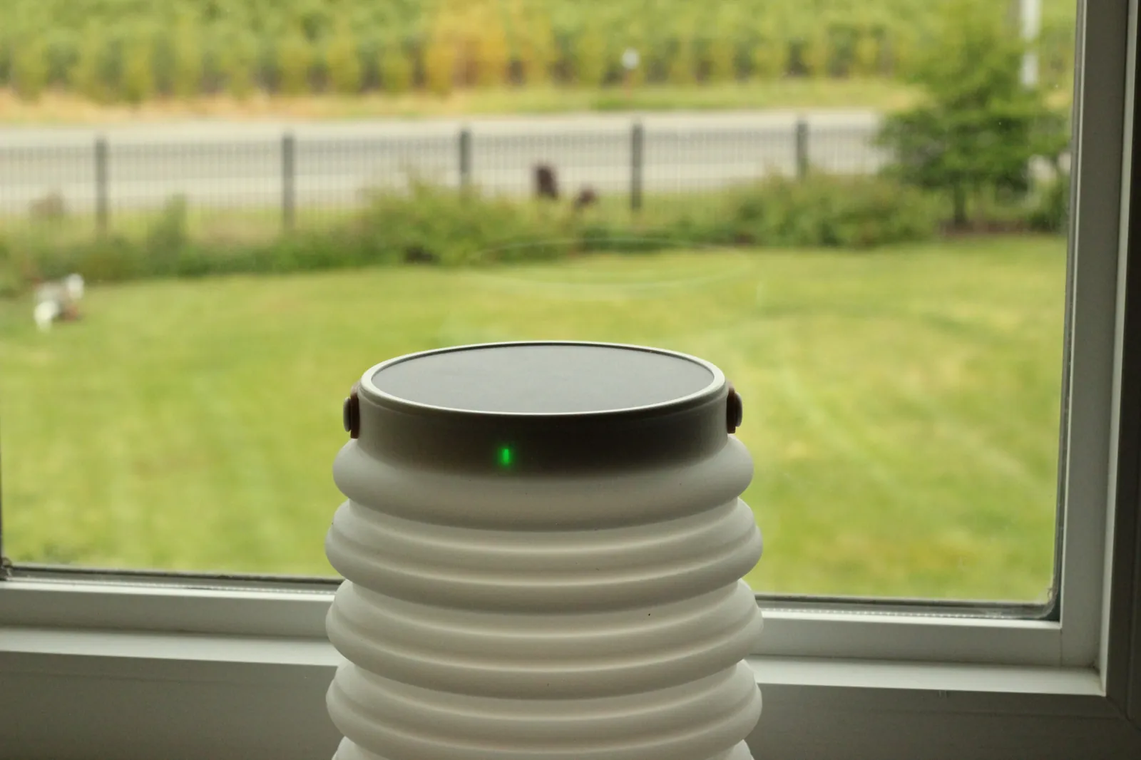 HAVEN 10000 on a windowsill with view of fenced yard outside, green charge LED glowing