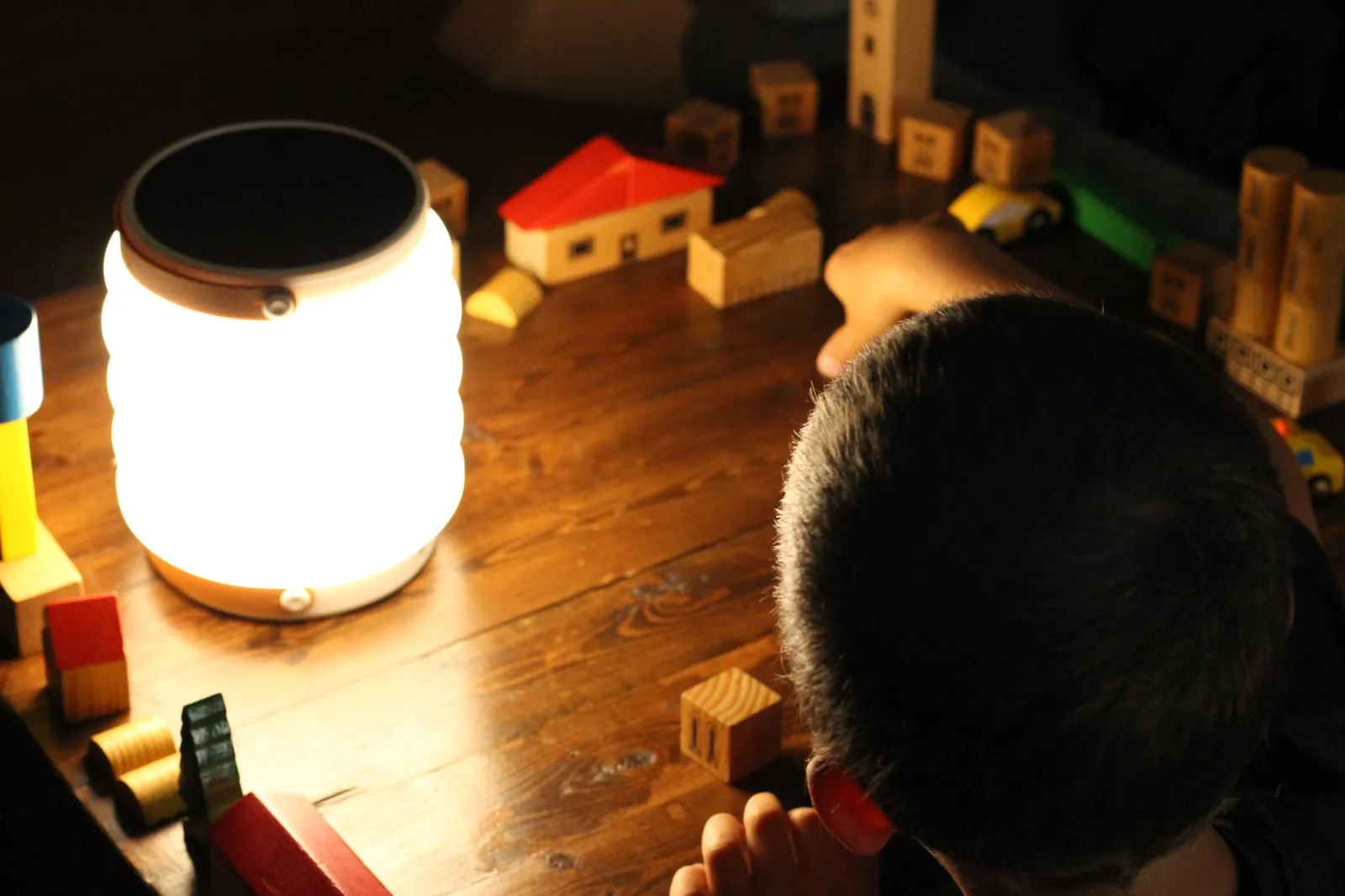 Child playing with wooden blocks beside the lit HAVEN 10000 on a wooden table