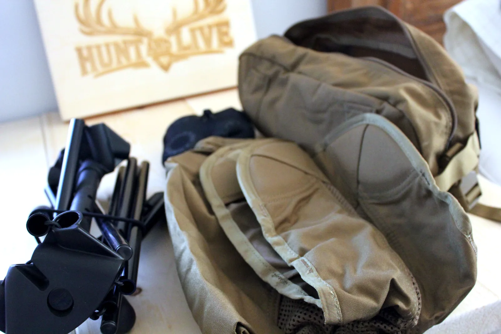 Two Helikon-Tex Traveler seats, one coyote and one adaptive green, lying beside their carry bags with the folded black pole bundles alongside