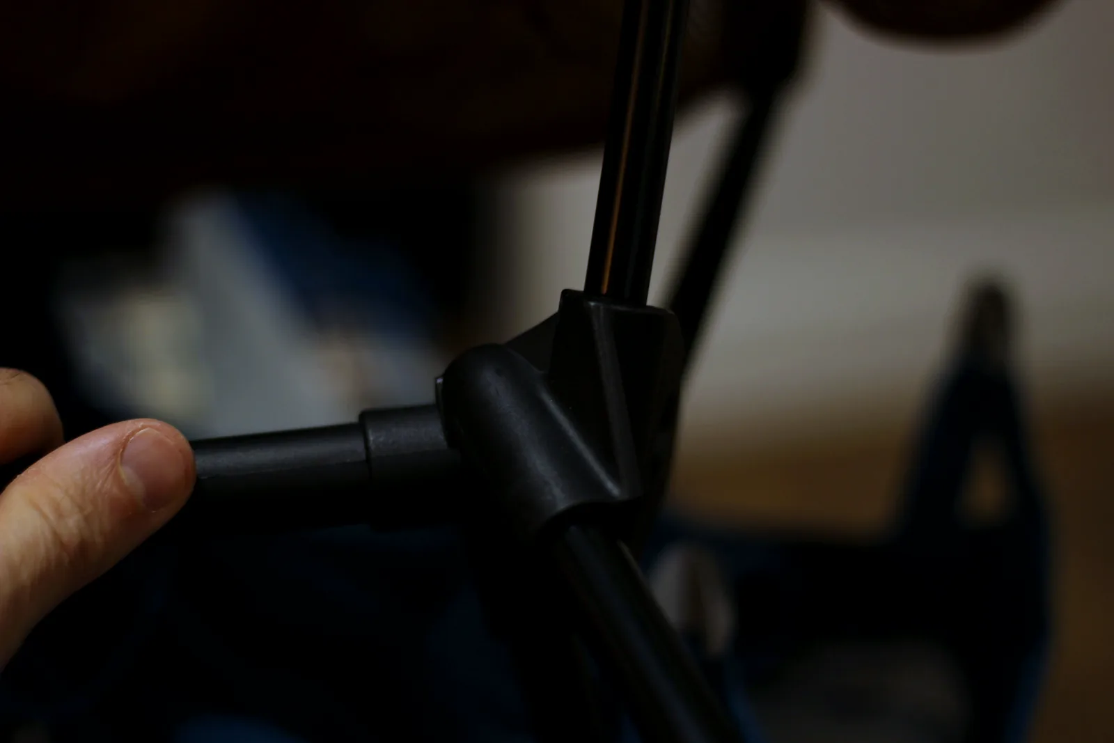 A hand holding a black moulded plastic hub with three aluminium pole ends converging into it