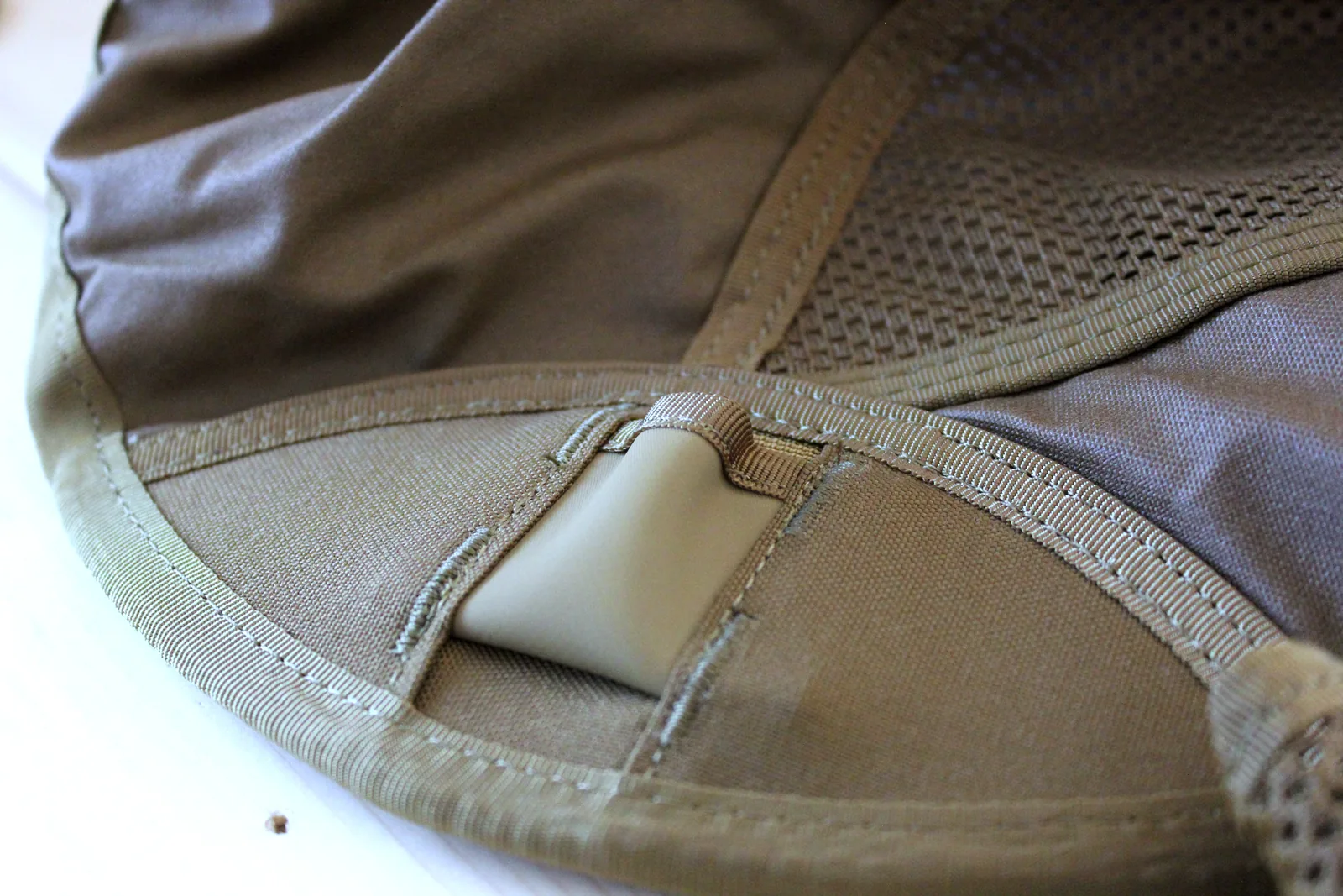 Close-up of the seat corner showing a webbing sleeve with a moulded tan plastic cup set into it