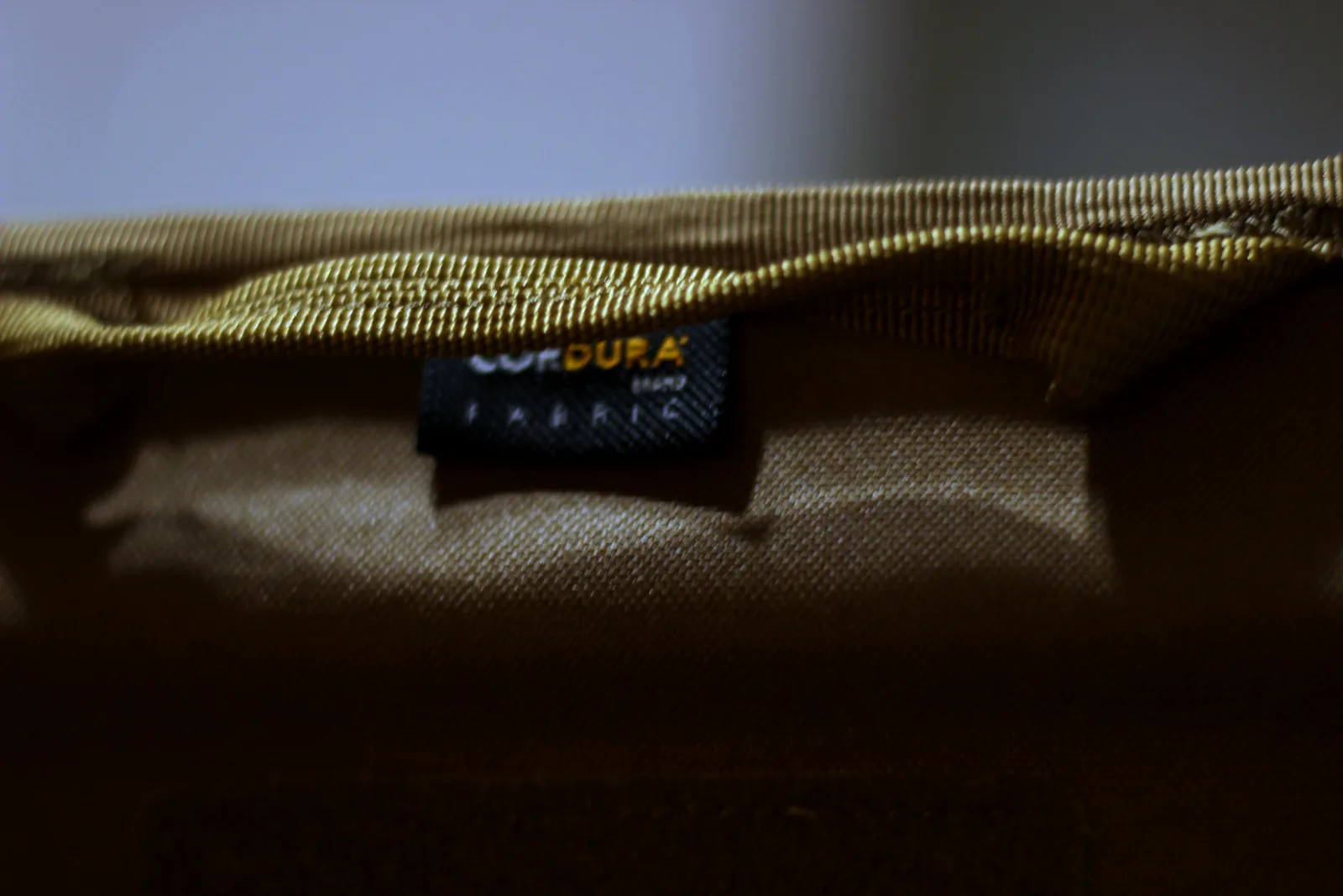 The CORDURA FABRIC label stitched into the hem of the coyote seat panel