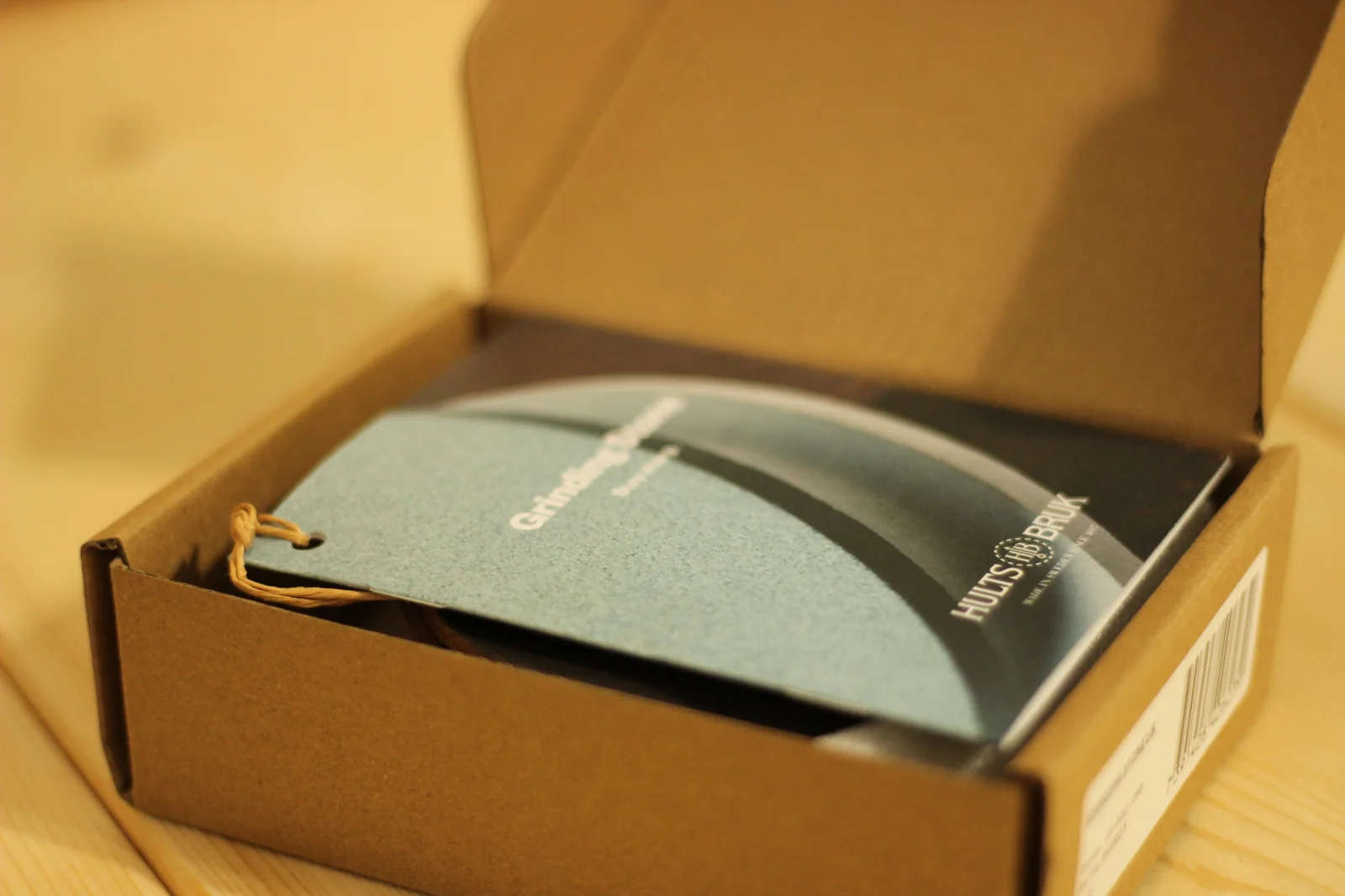 Opened grinding stone box with the booklet visible inside featuring the stone product photo on the cover