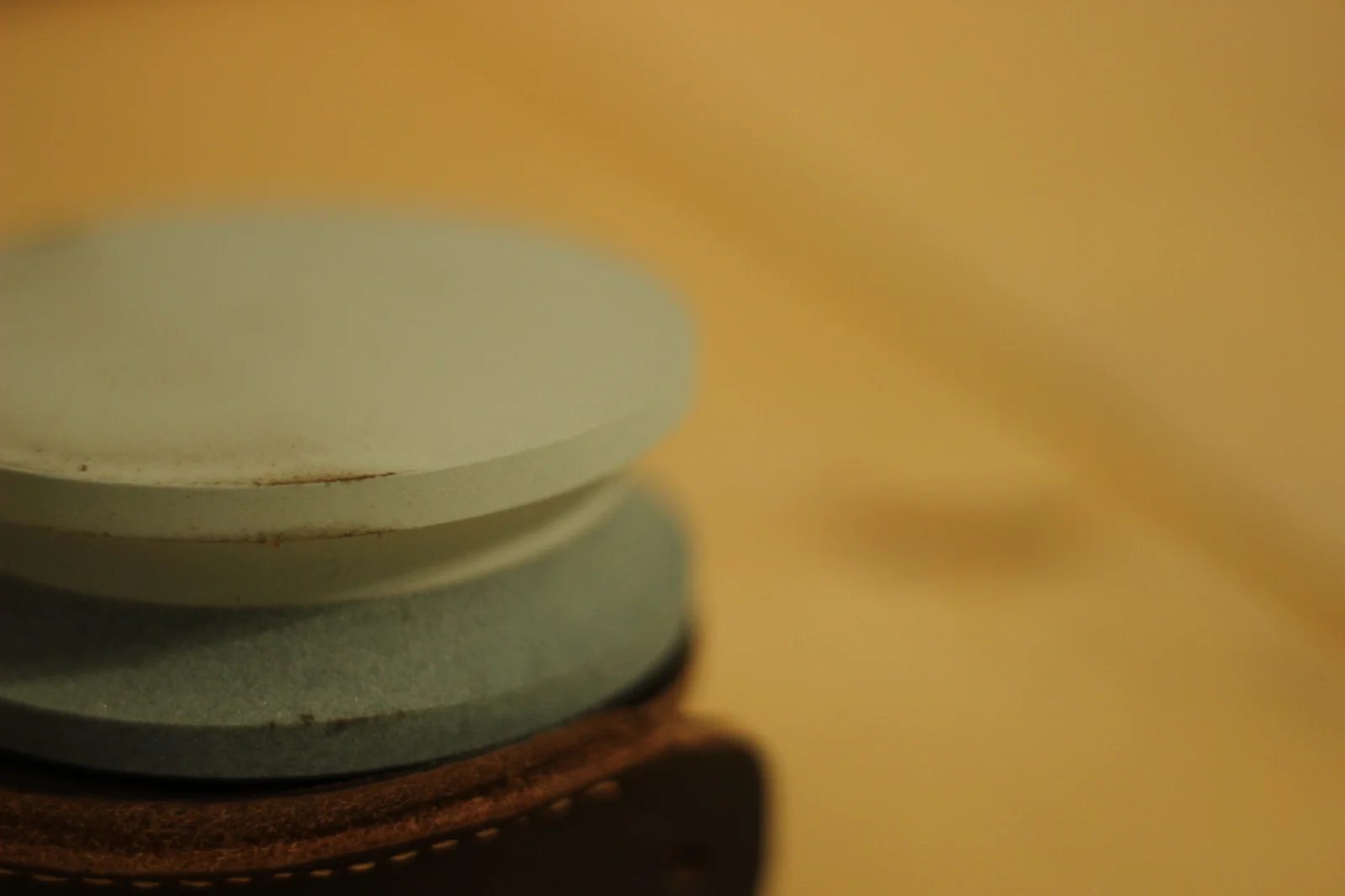 Side profile of the grinding stone showing the lighter coloured top face and slightly darker bottom face stacked as one disc