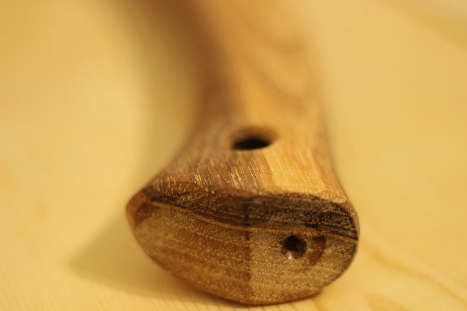 Macro shot of the end of the hickory handle showing the cross-grain pattern and the drilled thong hole